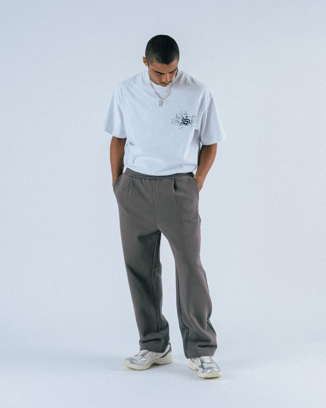 Person wearing a white hoodie and gray pants on a white background