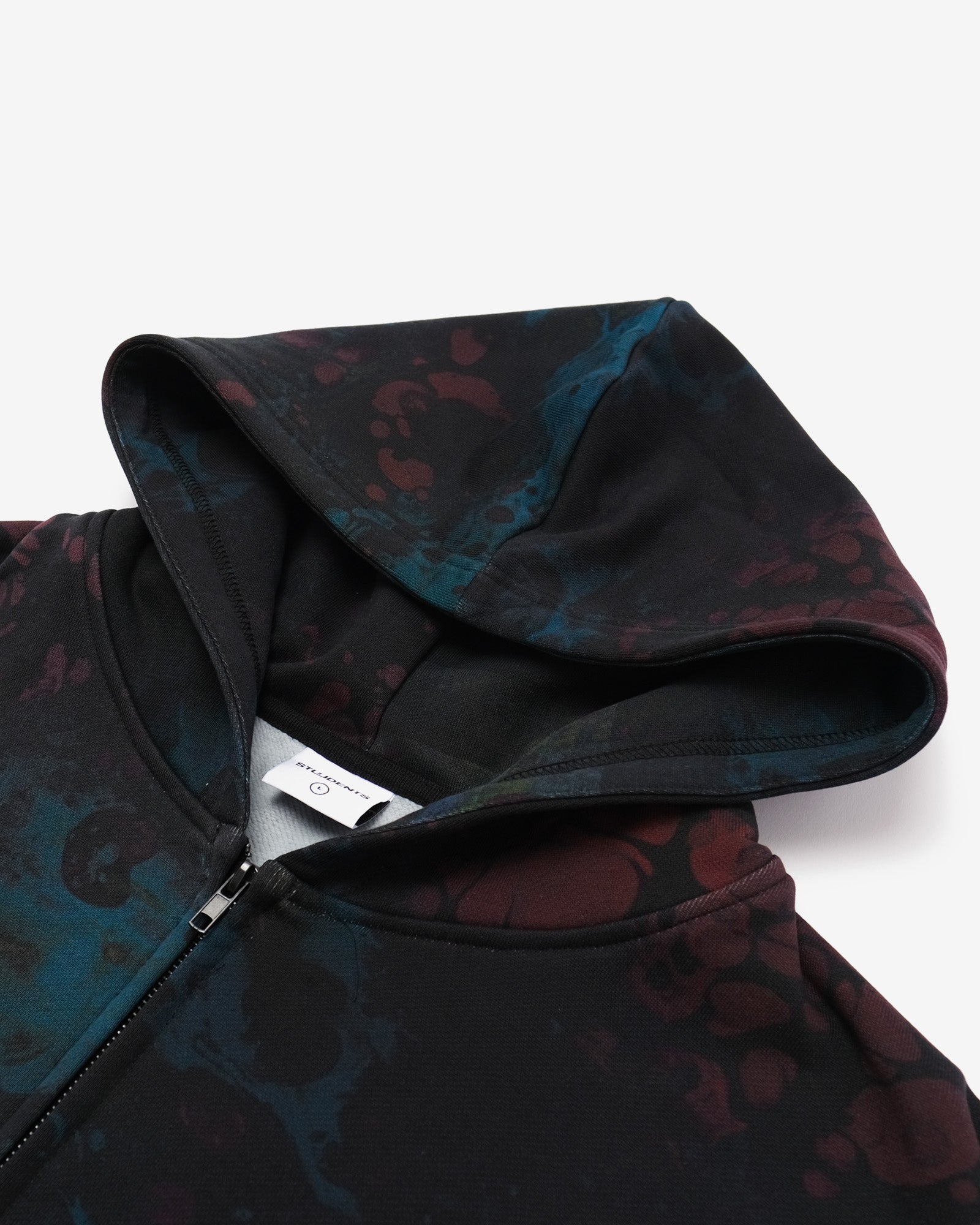 Close-up of a dark patterned hoodie with a brand label on a light gray background