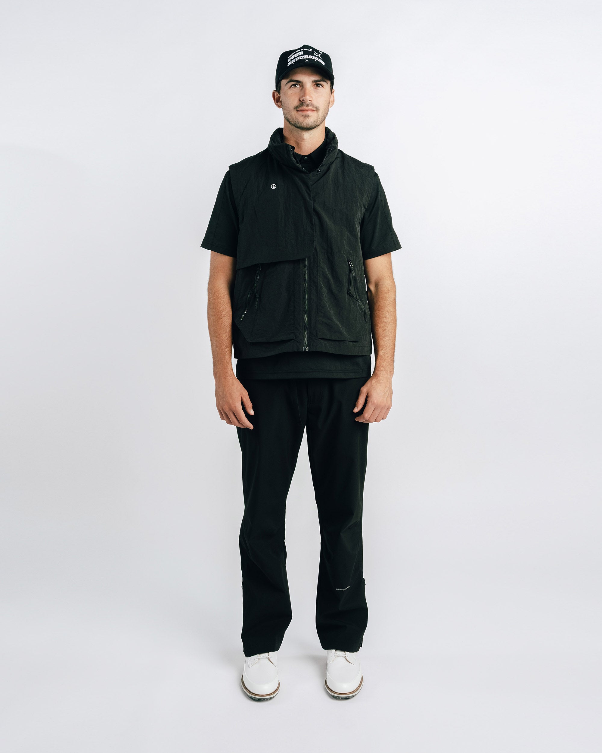 Man wearing a black vest, pants, and cap on a white background