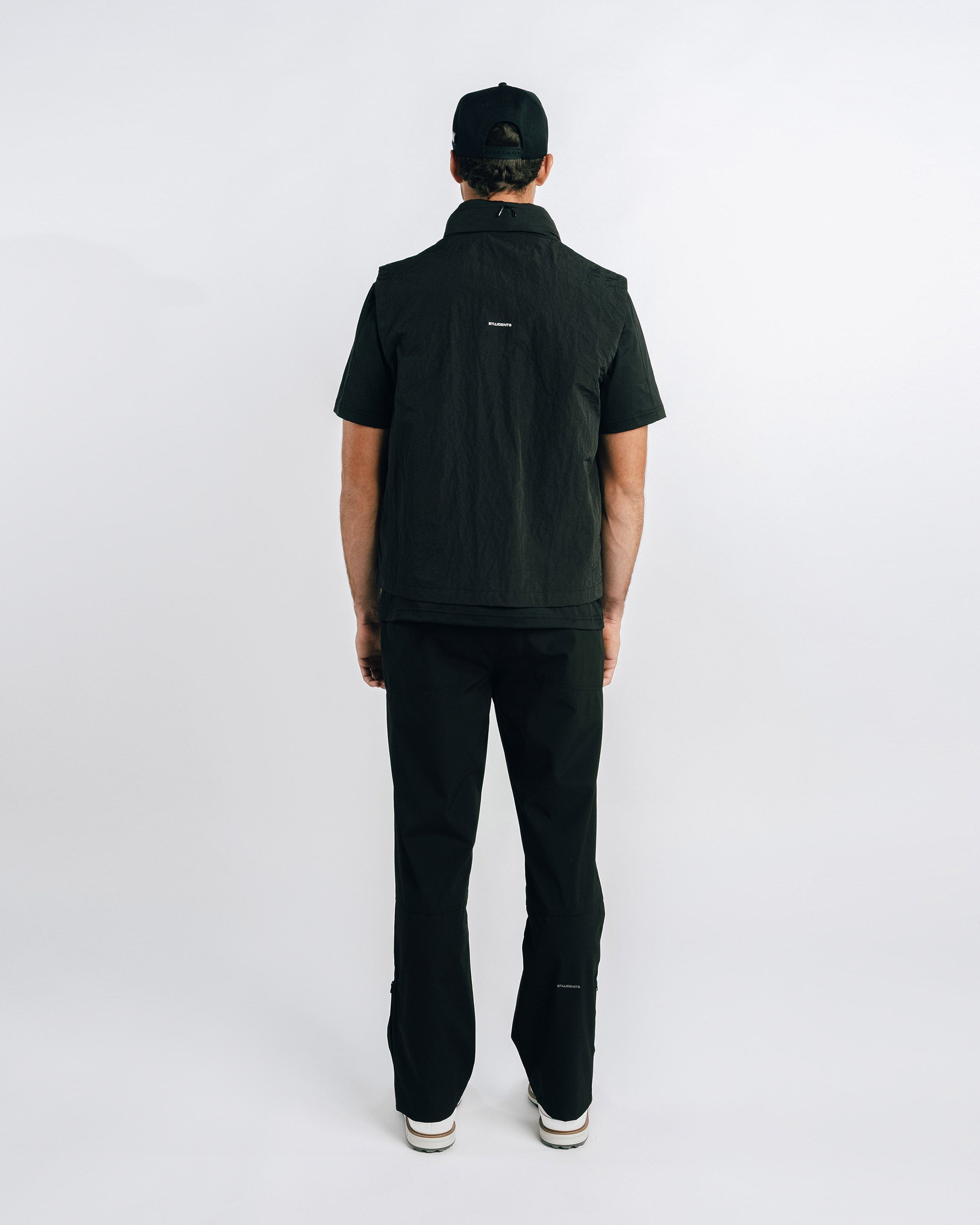 Person wearing a black jacket and pants on a white background