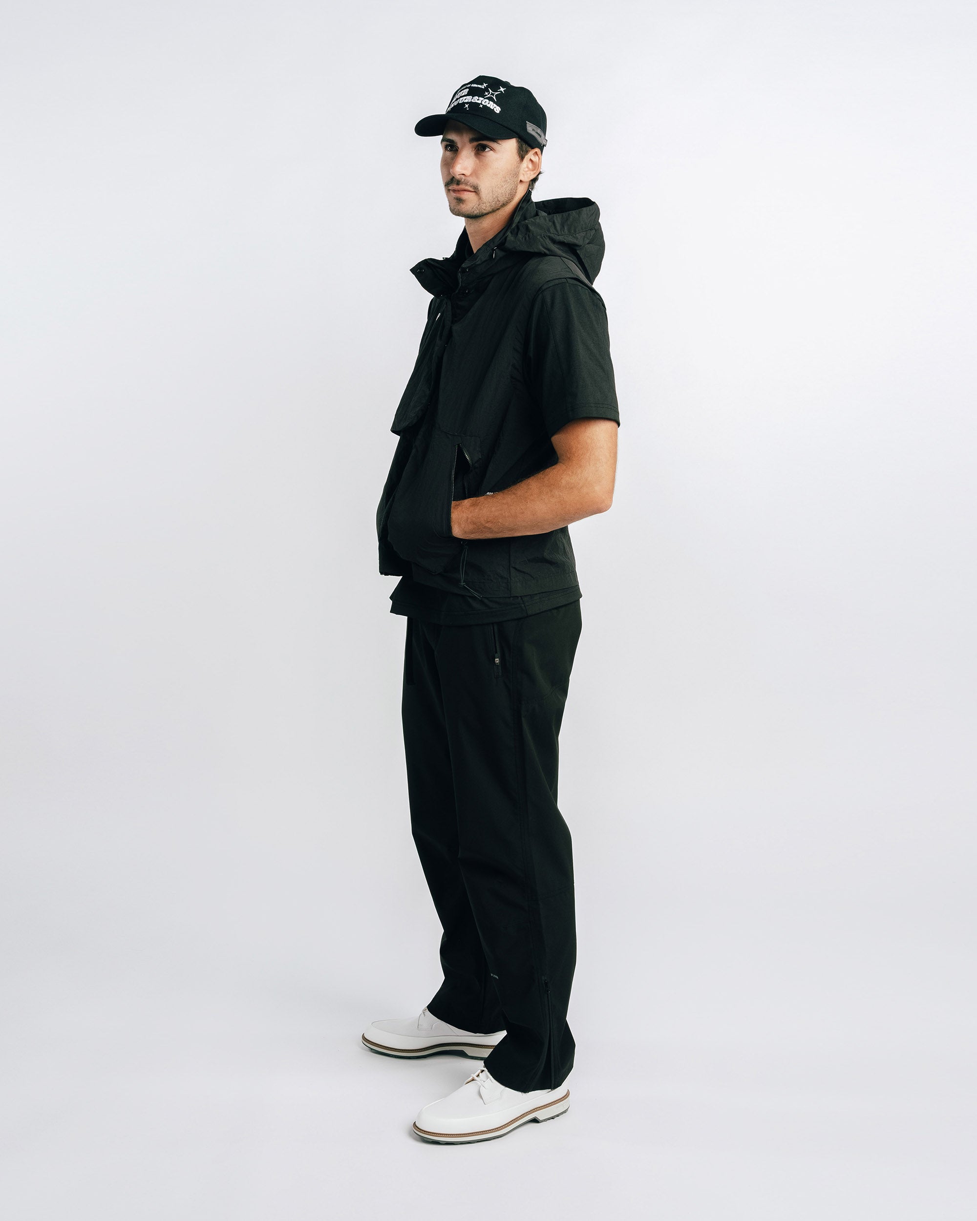 Man wearing a black outfit with a cap on a white background