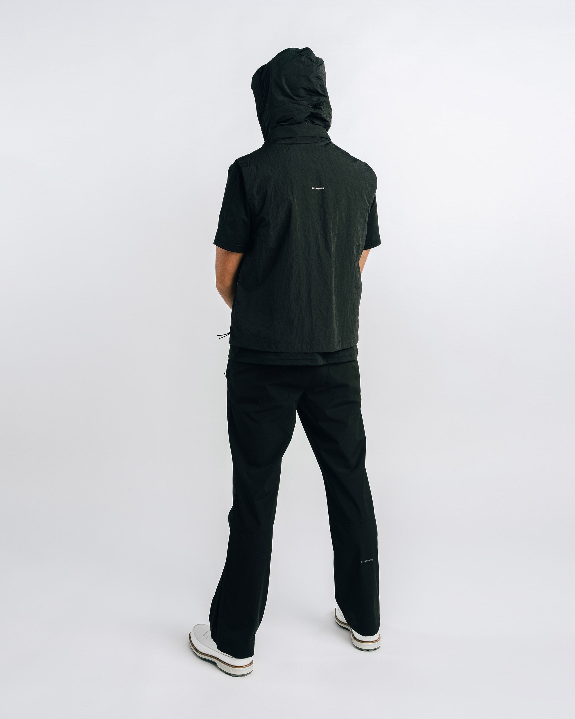 Person wearing a black hoodie and pants on a white background