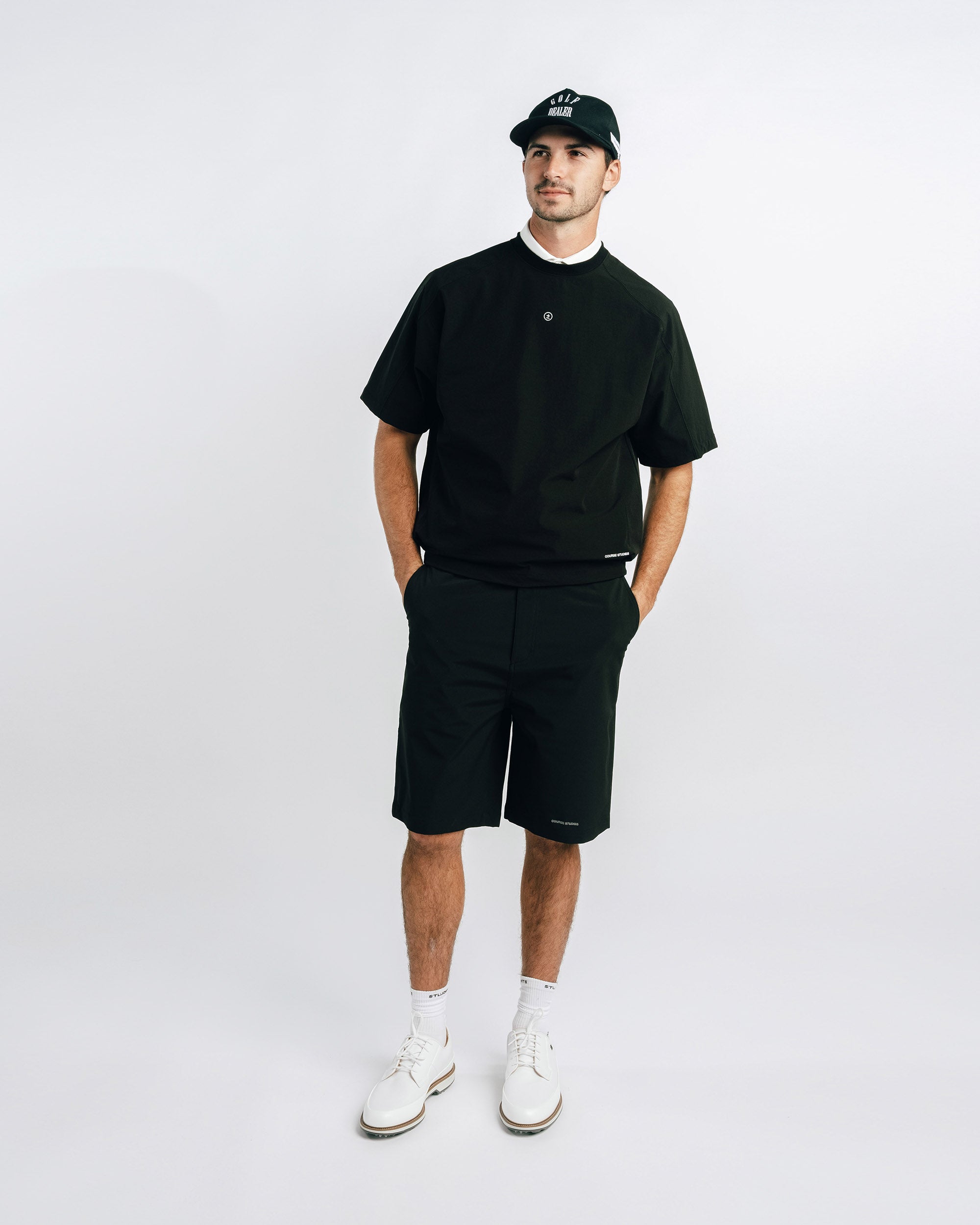 Man wearing a black t-shirt, shorts, and cap on a white background