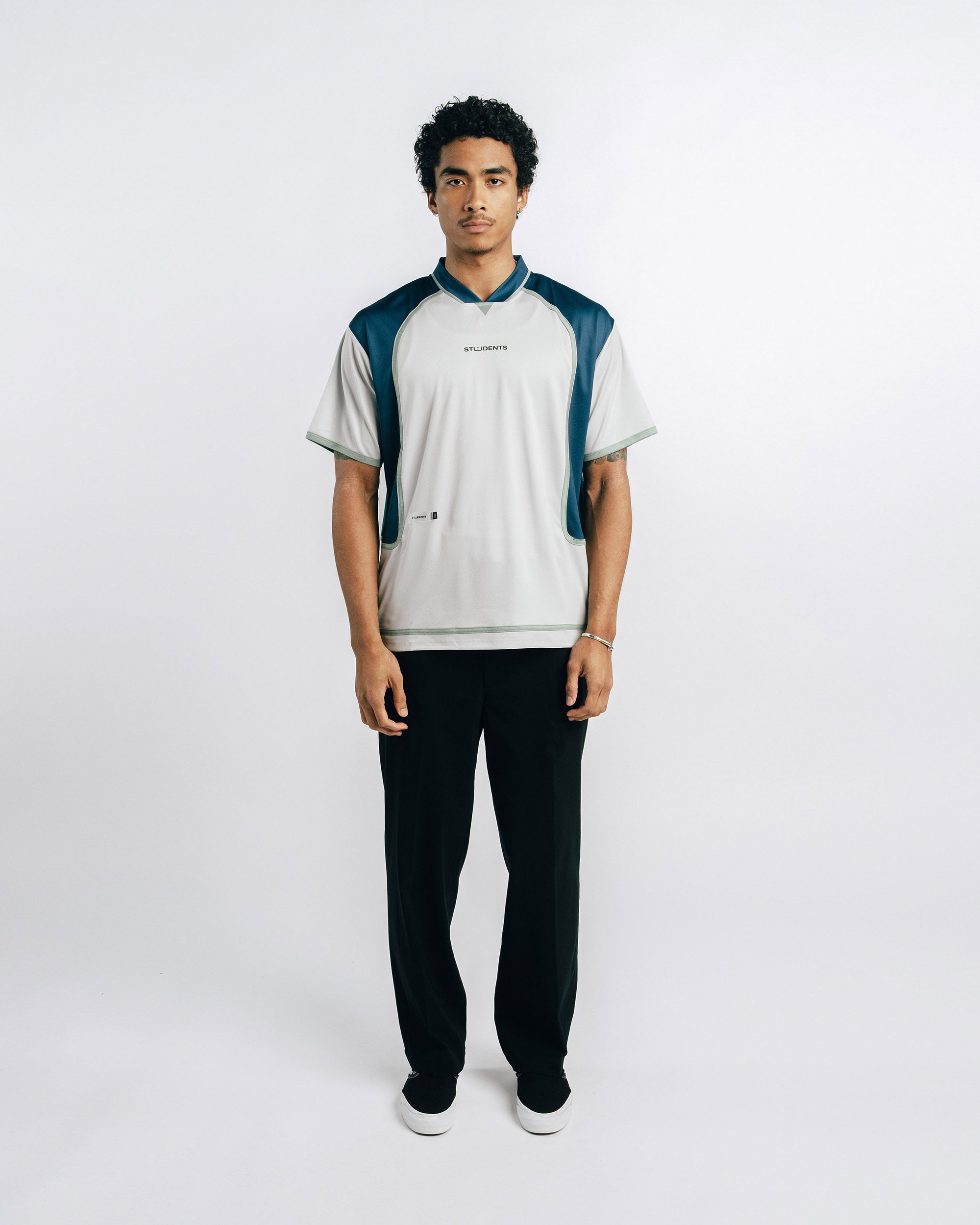 Person wearing a white and blue shirt with black pants on a white background