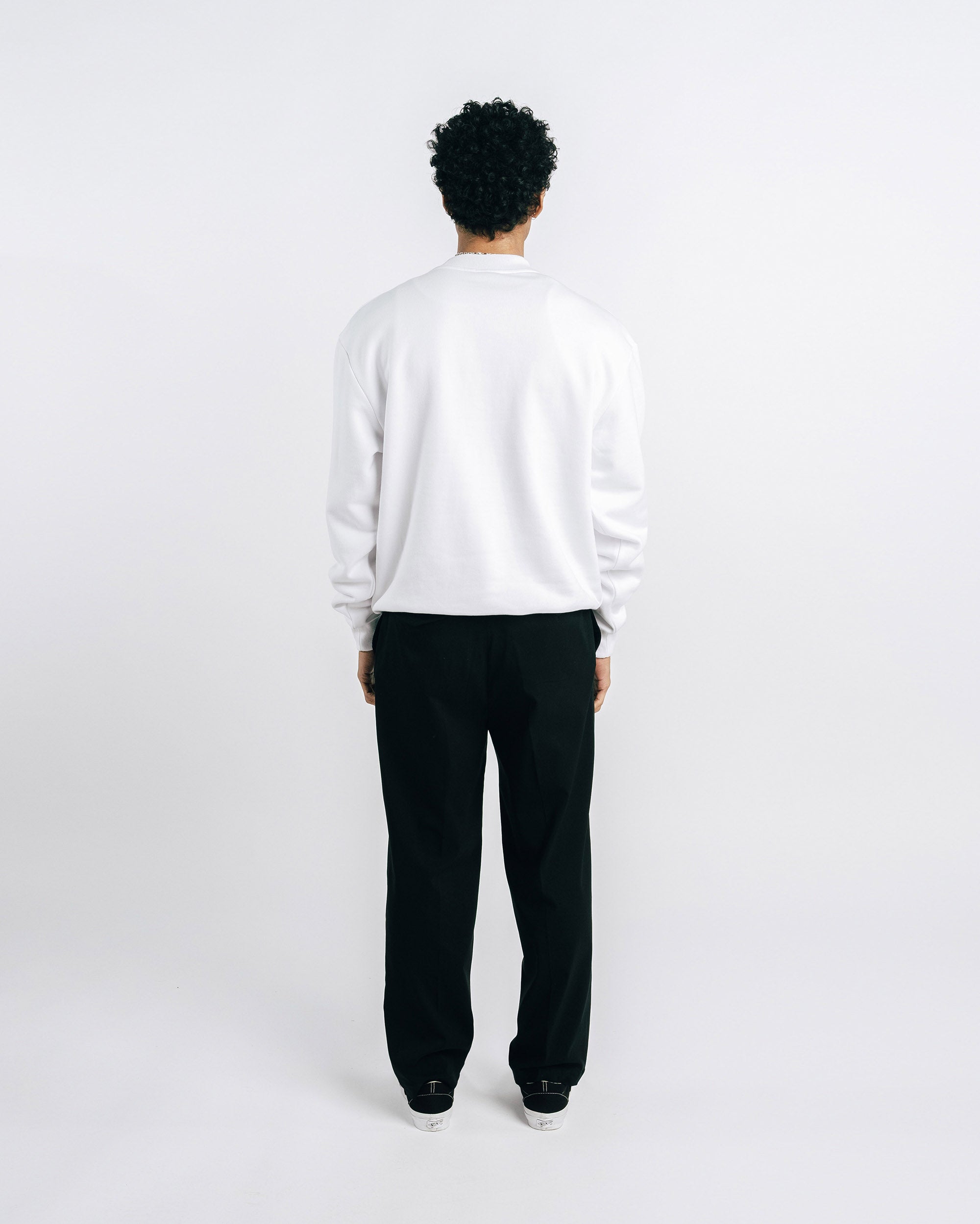 Person wearing a white sweater and black pants on a white background