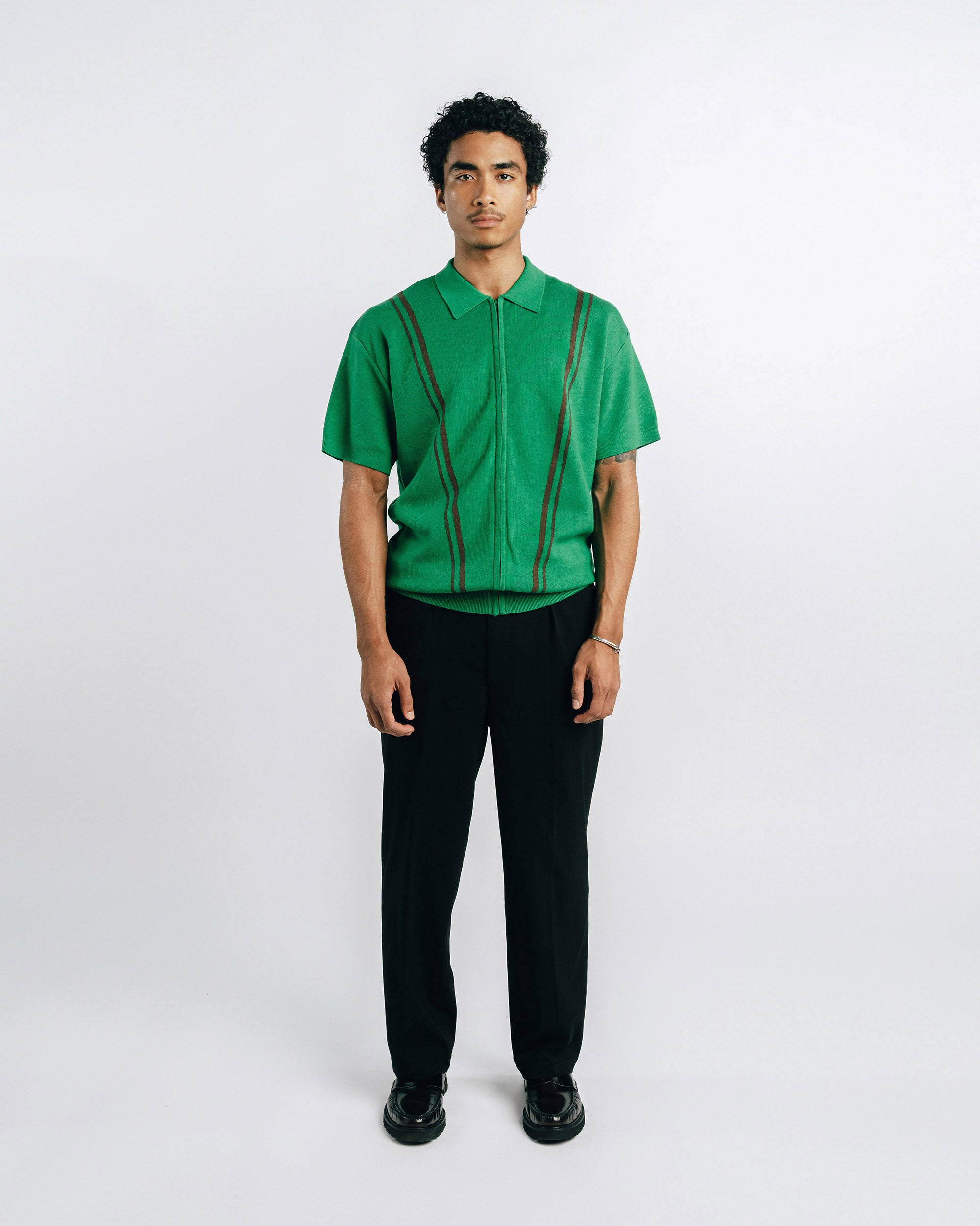 Person wearing a green shirt with suspenders on a white background