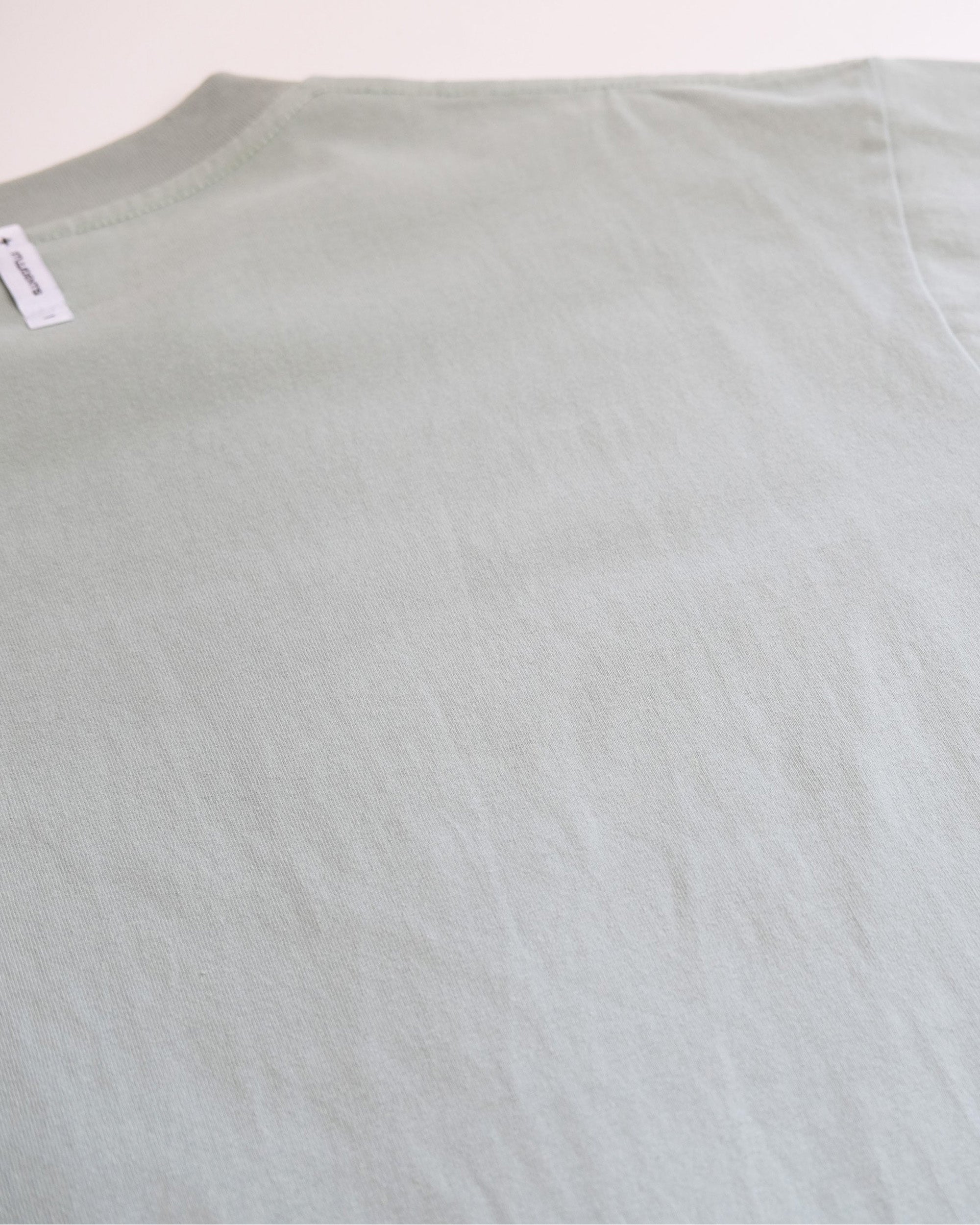 Light green t-shirt with a tag on a white background