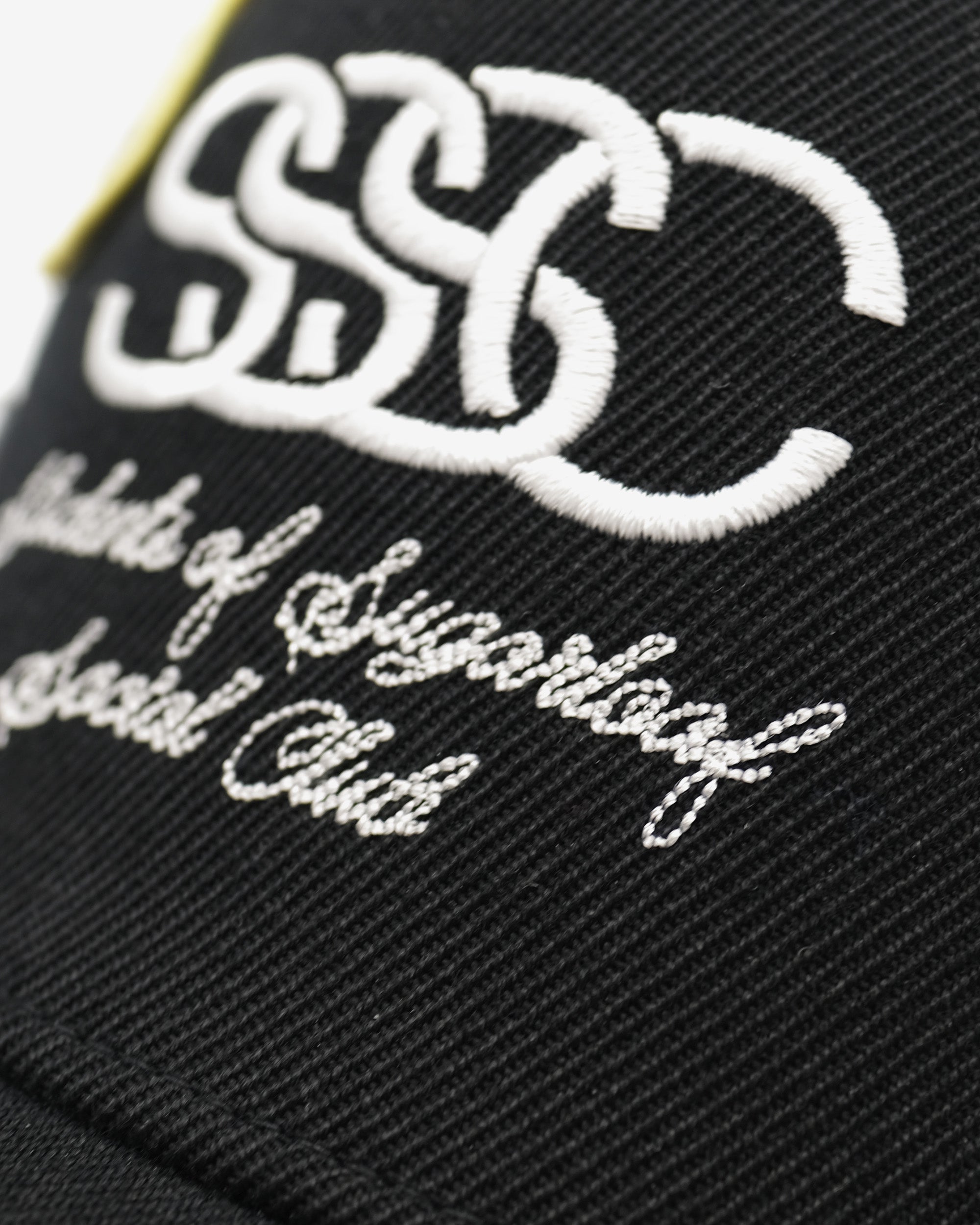 Black fabric with white embroidered text and logo