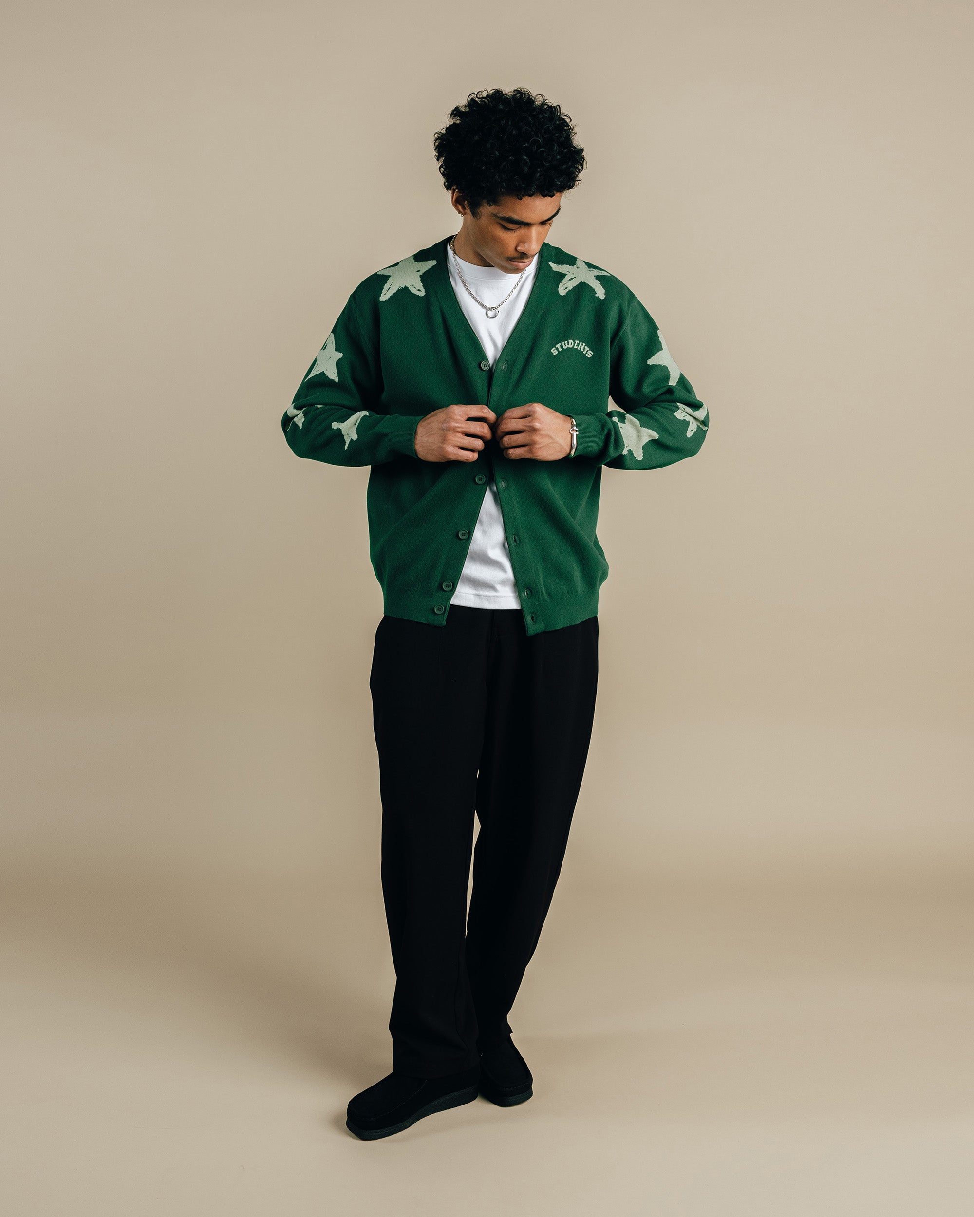 Person wearing a green cardigan with white patterns on a beige background