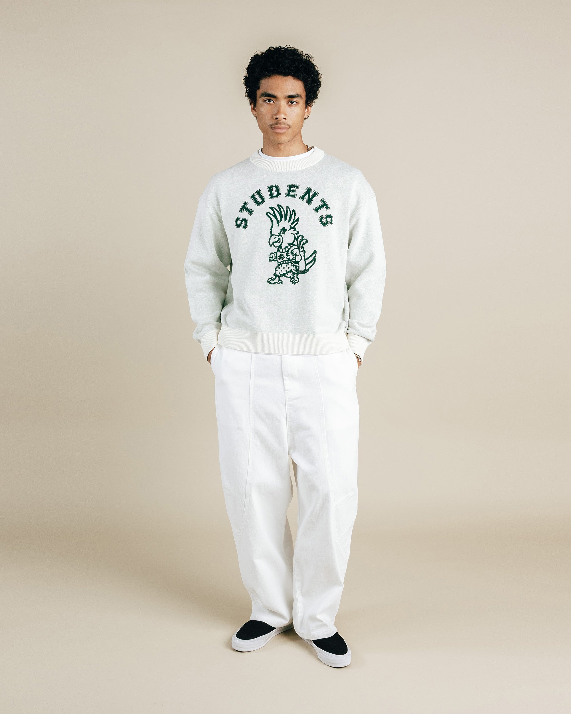 Person wearing a white sweatshirt with 'STUDENTS' and a graphic design on a beige background