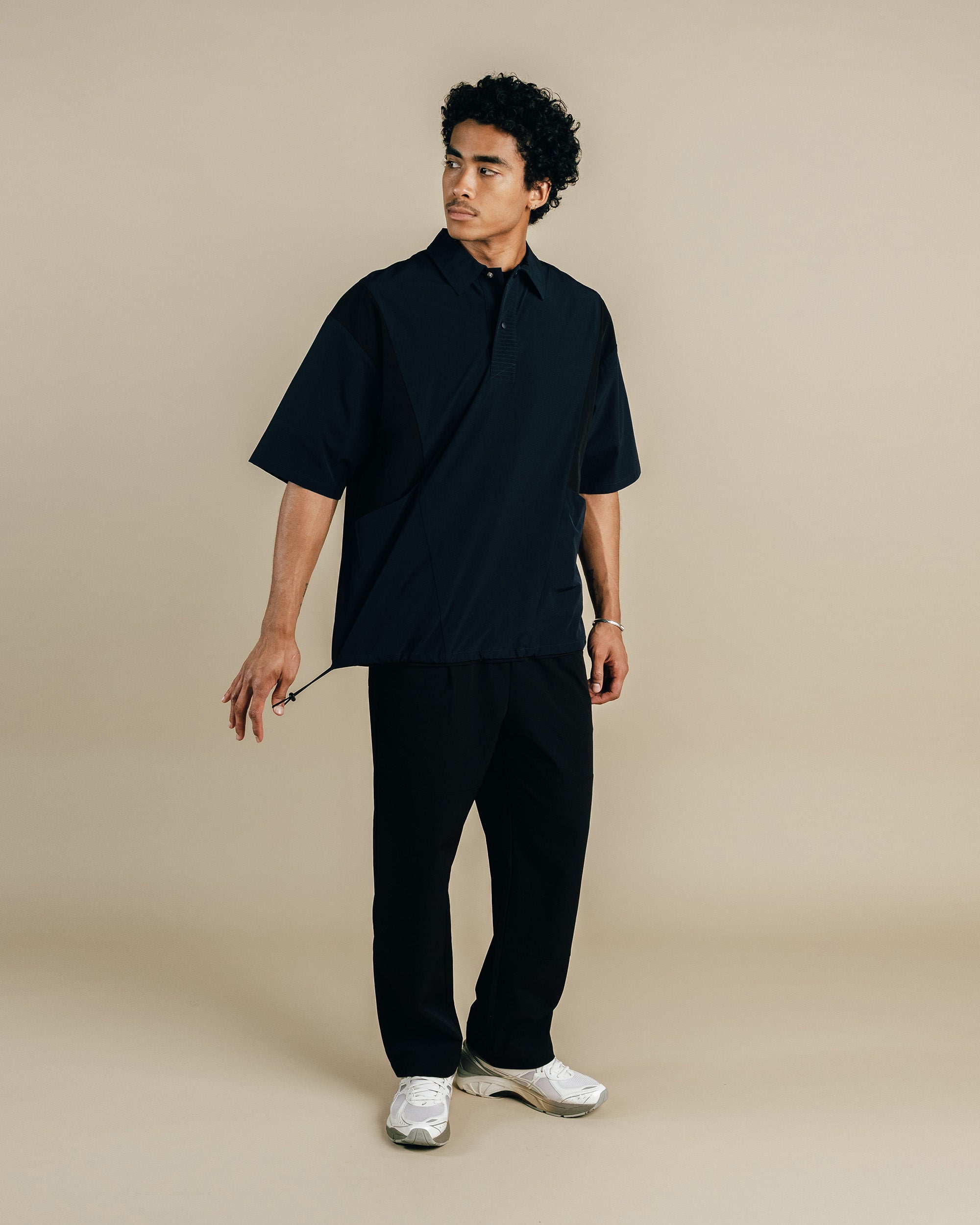 Man wearing a black shirt and pants on a beige background