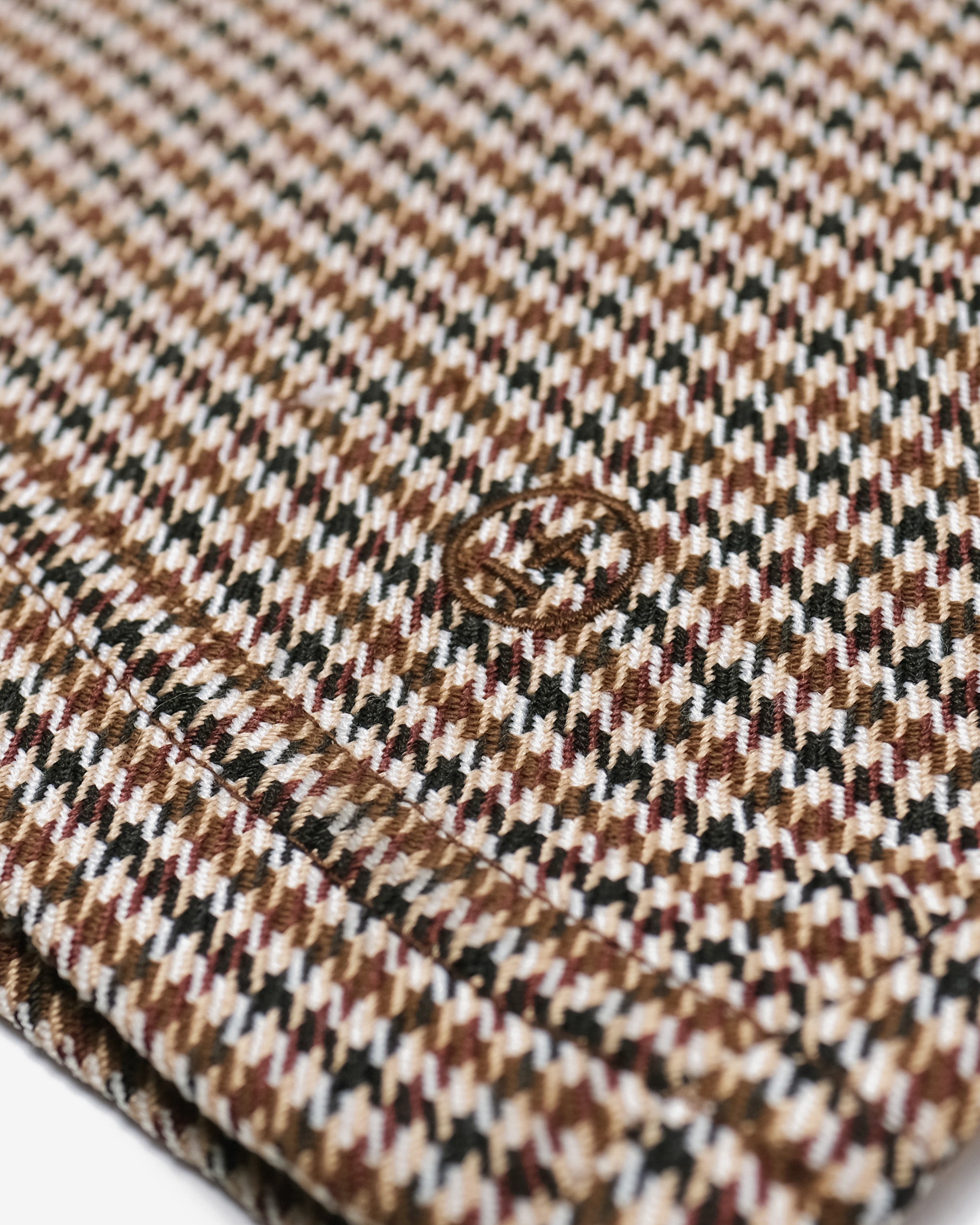 Close-up of a houndstooth patterned fabric with a brand logo.