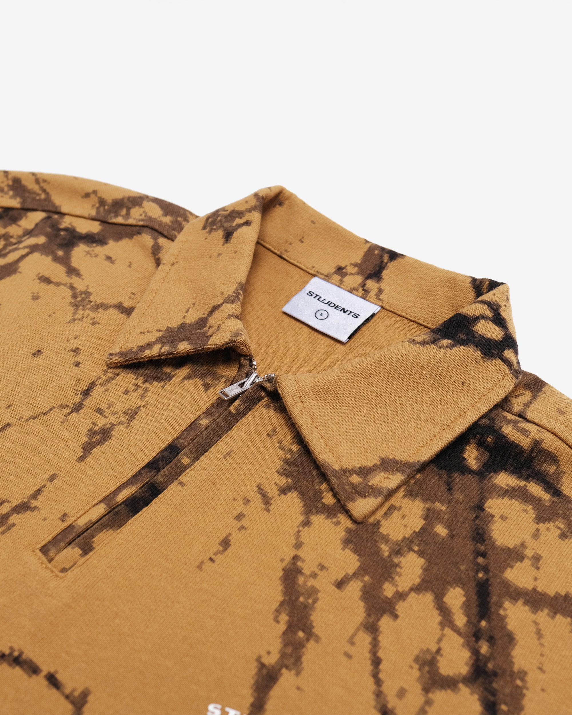 Close-up of a mustard yellow shirt with tie-dye pattern and brand label on collar.