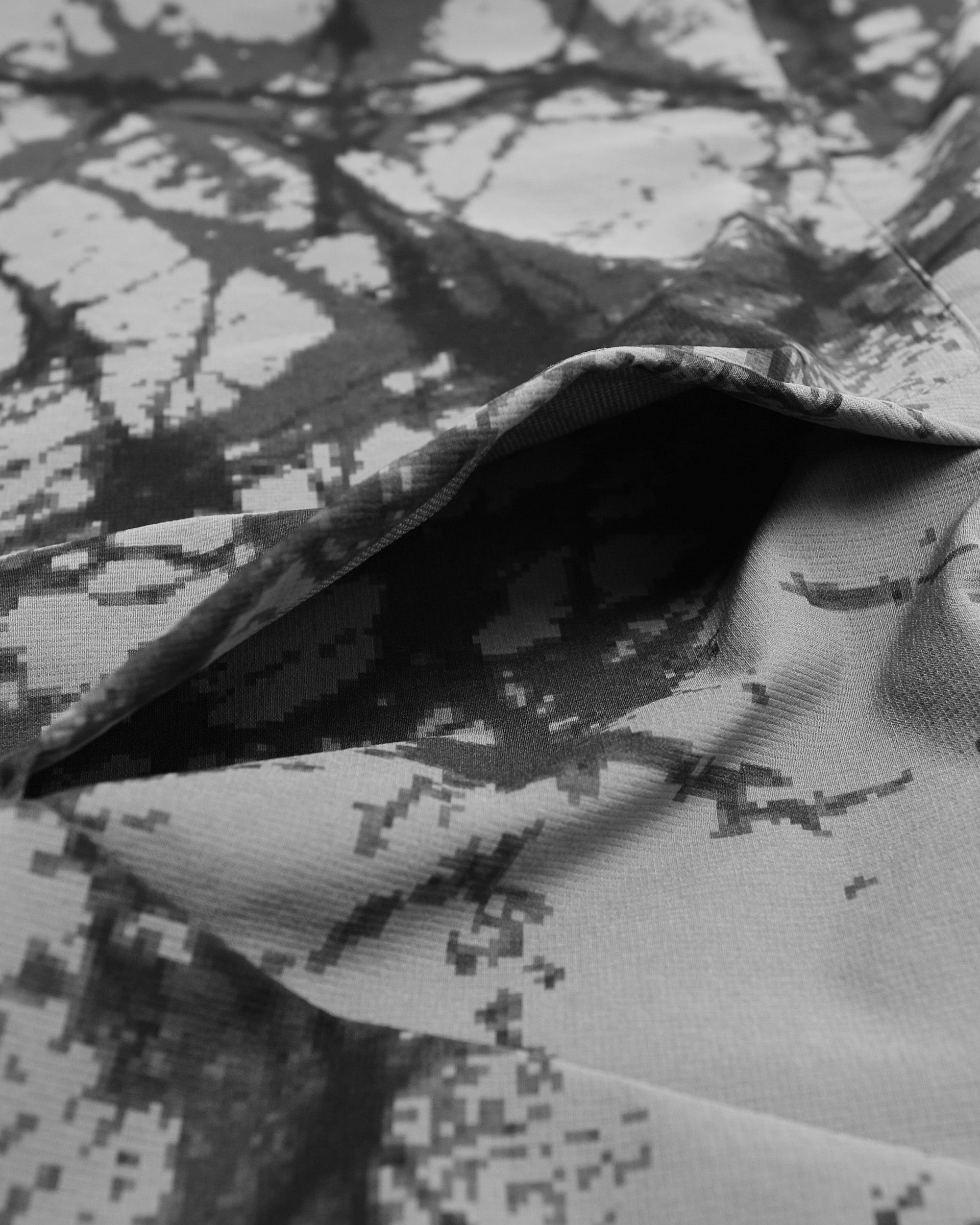 Close-up of a camouflage-patterned fabric with a focus on texture and pattern.