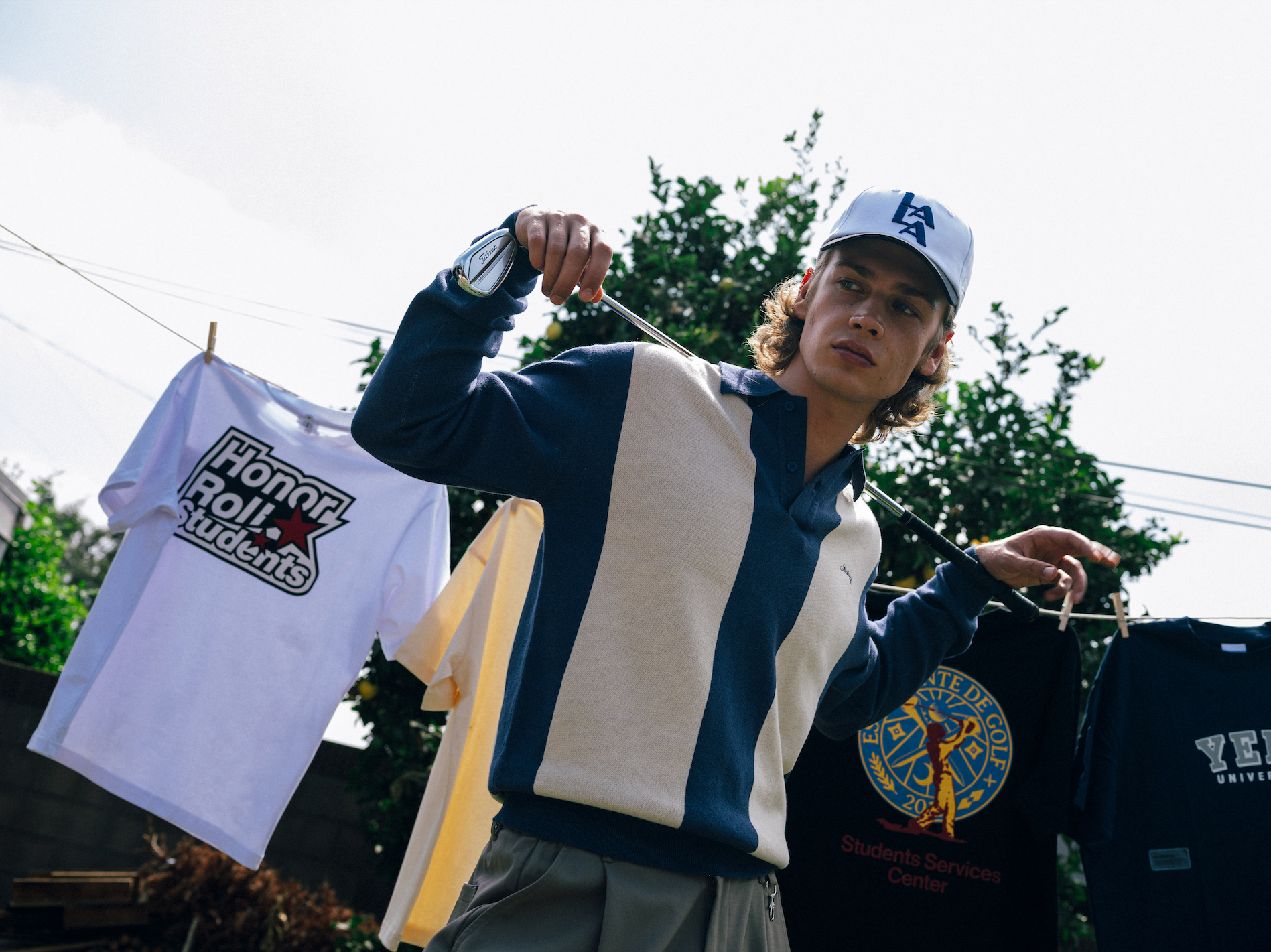 Person holding t-shirts with visible text and logos outdoors