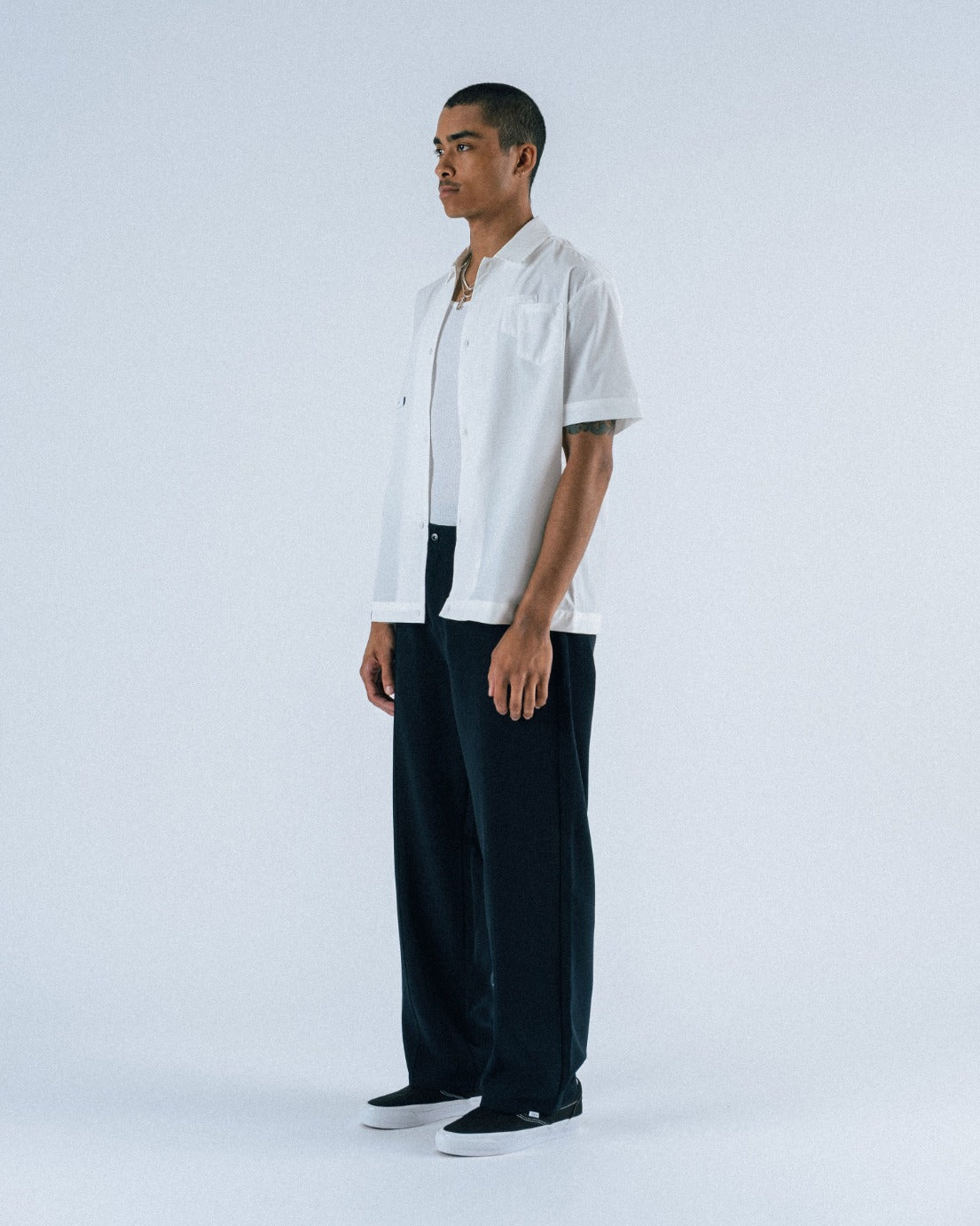 Person wearing a white shirt and dark pants on a white background