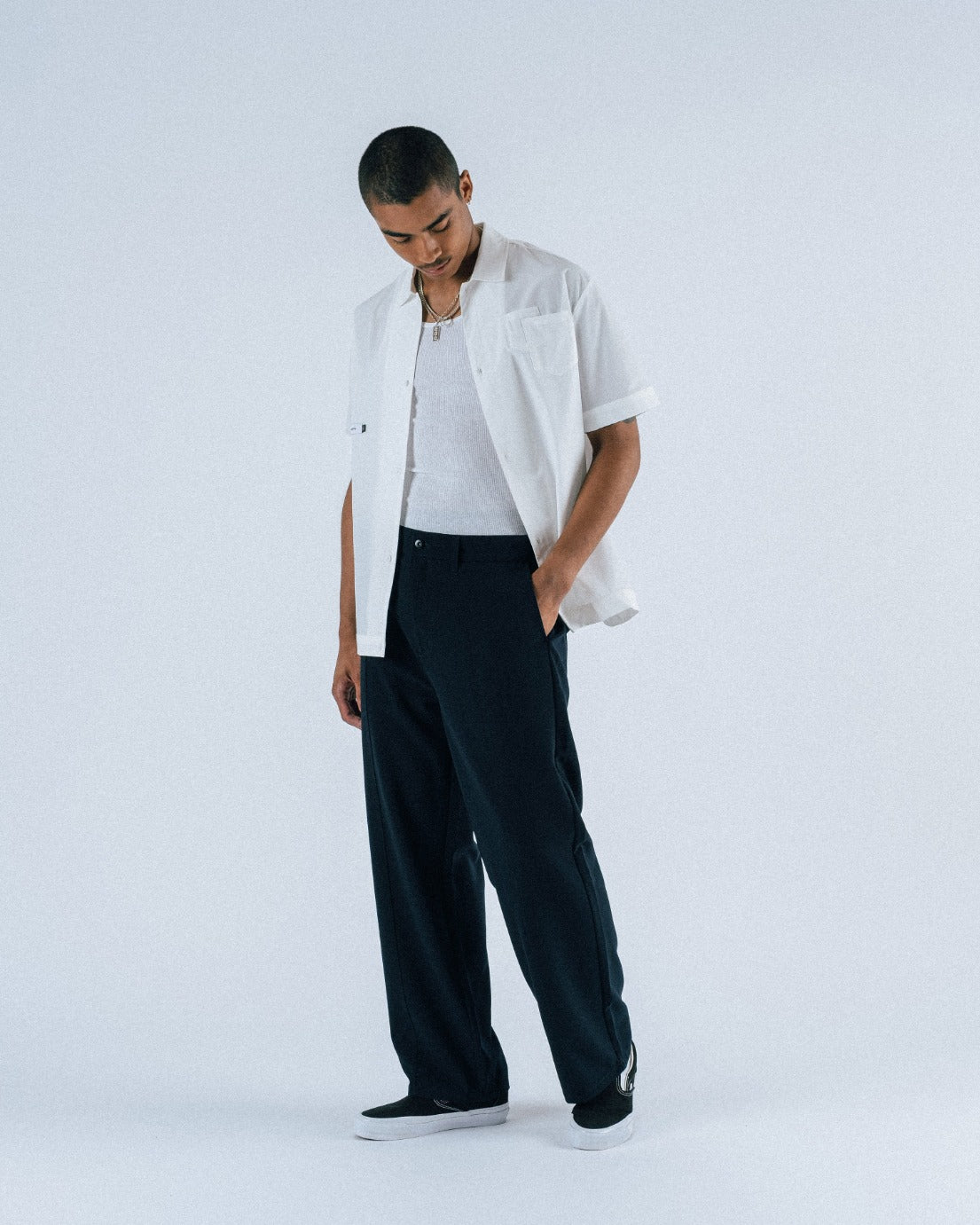 Person wearing a white jacket, white shirt, and black pants on a white background