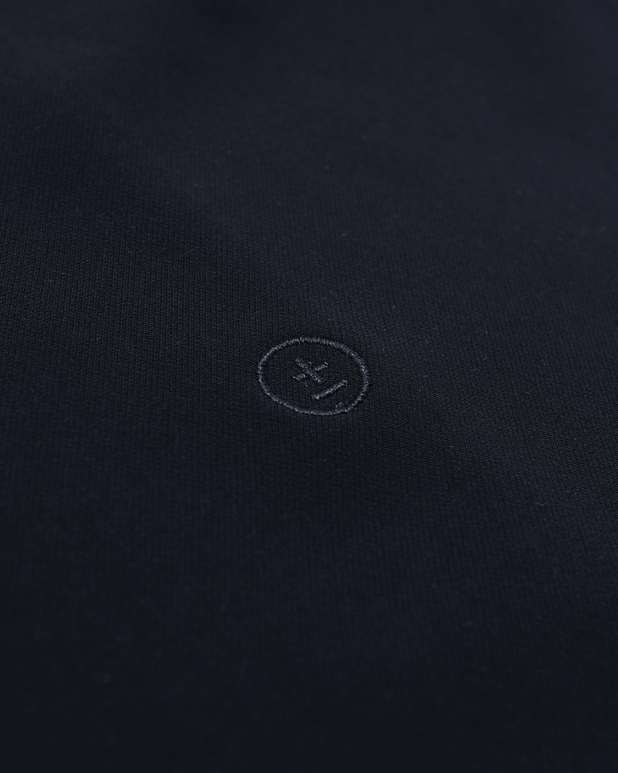 Close-up of a dark fabric surface with a small logo or emblem.