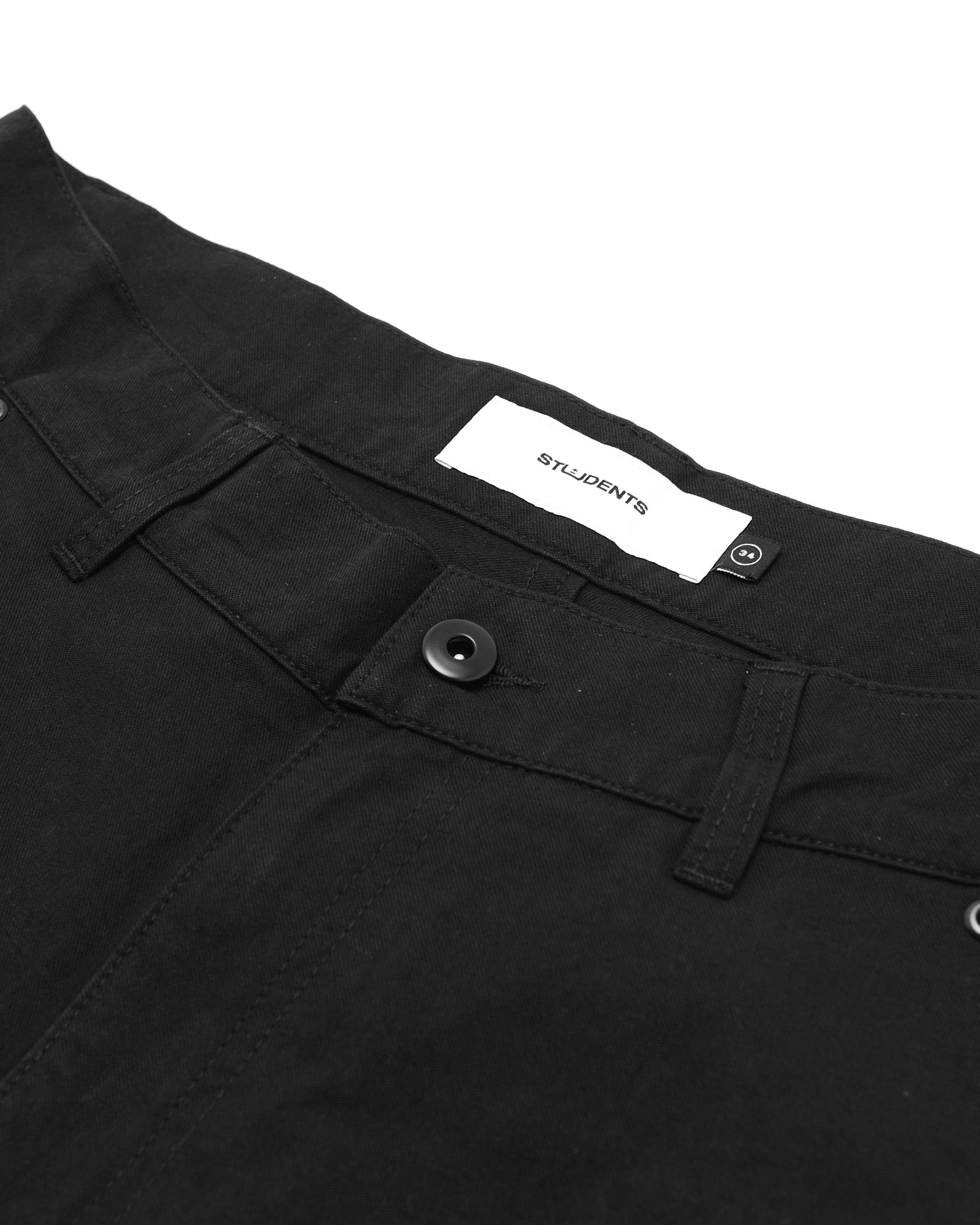Close-up of black pants with a brand label on a white background