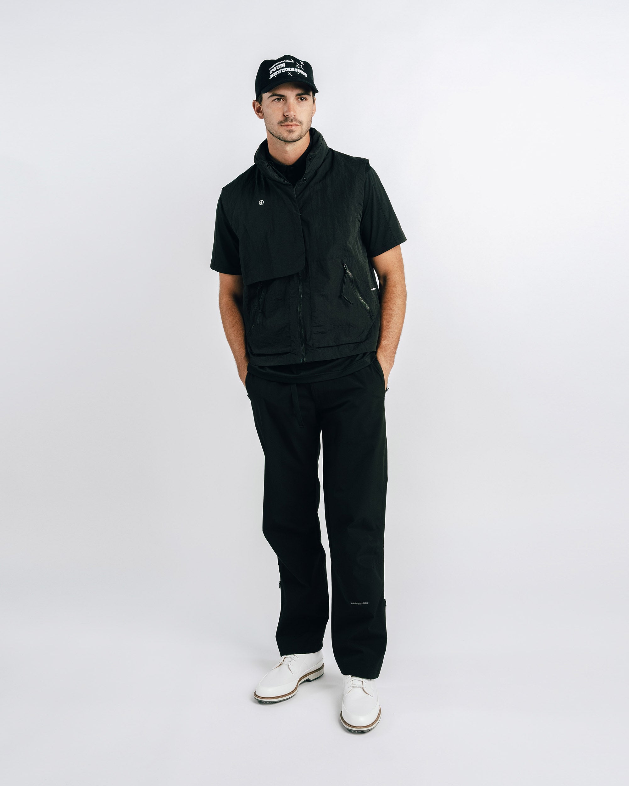Person wearing a black outfit with a cap on a white background