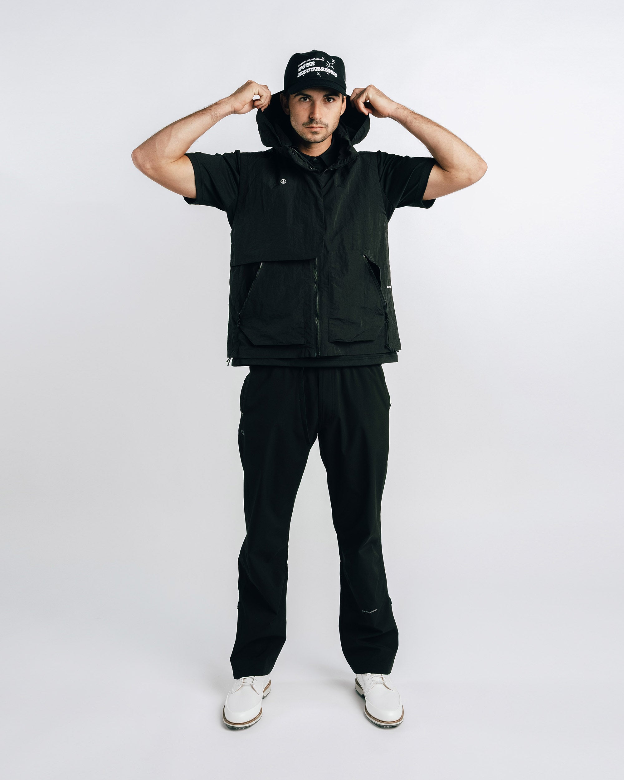 Person wearing a black outfit with a cap on a white background