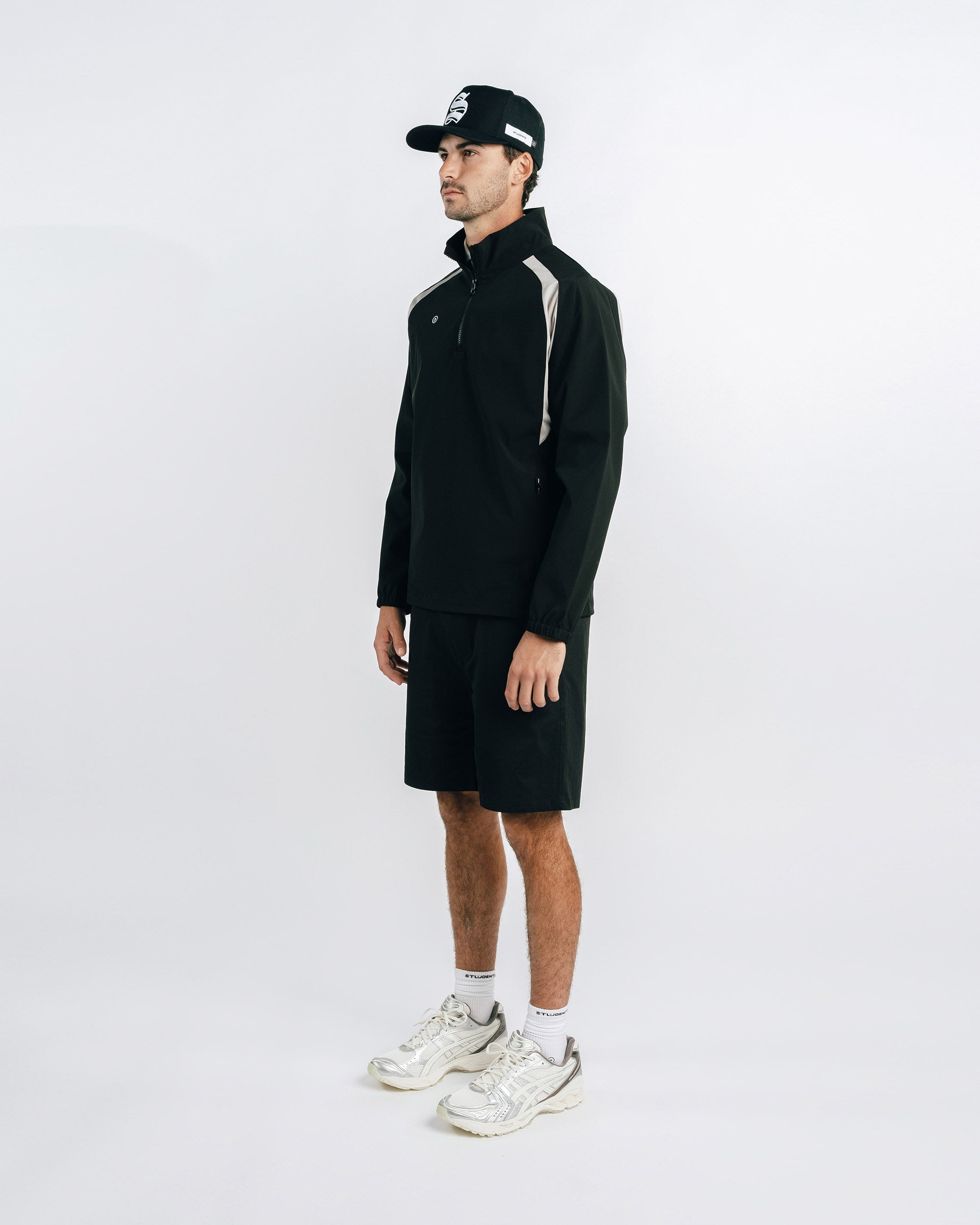 Man wearing a black outfit with a cap on a white background