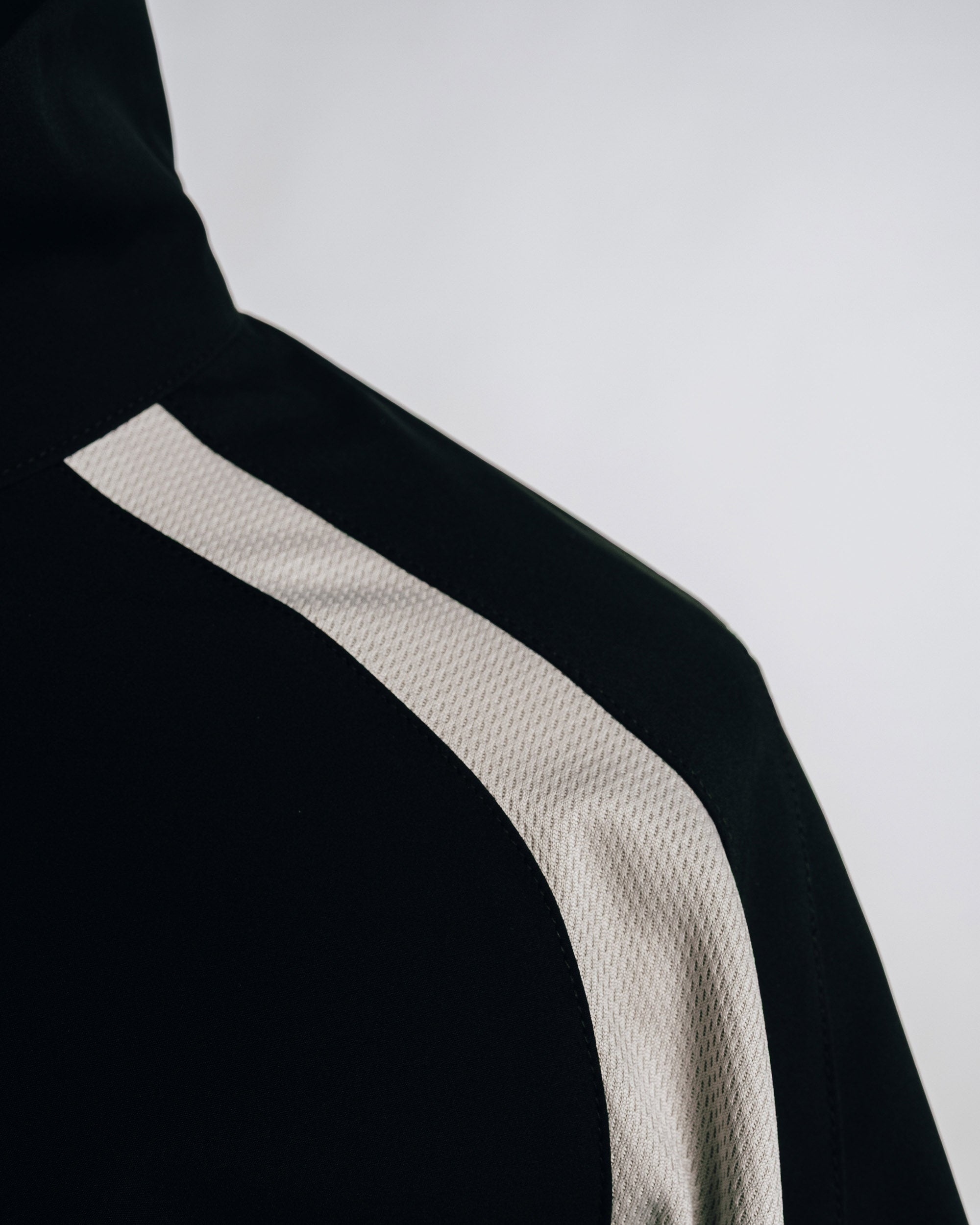 Black garment with a beige stripe on a white background