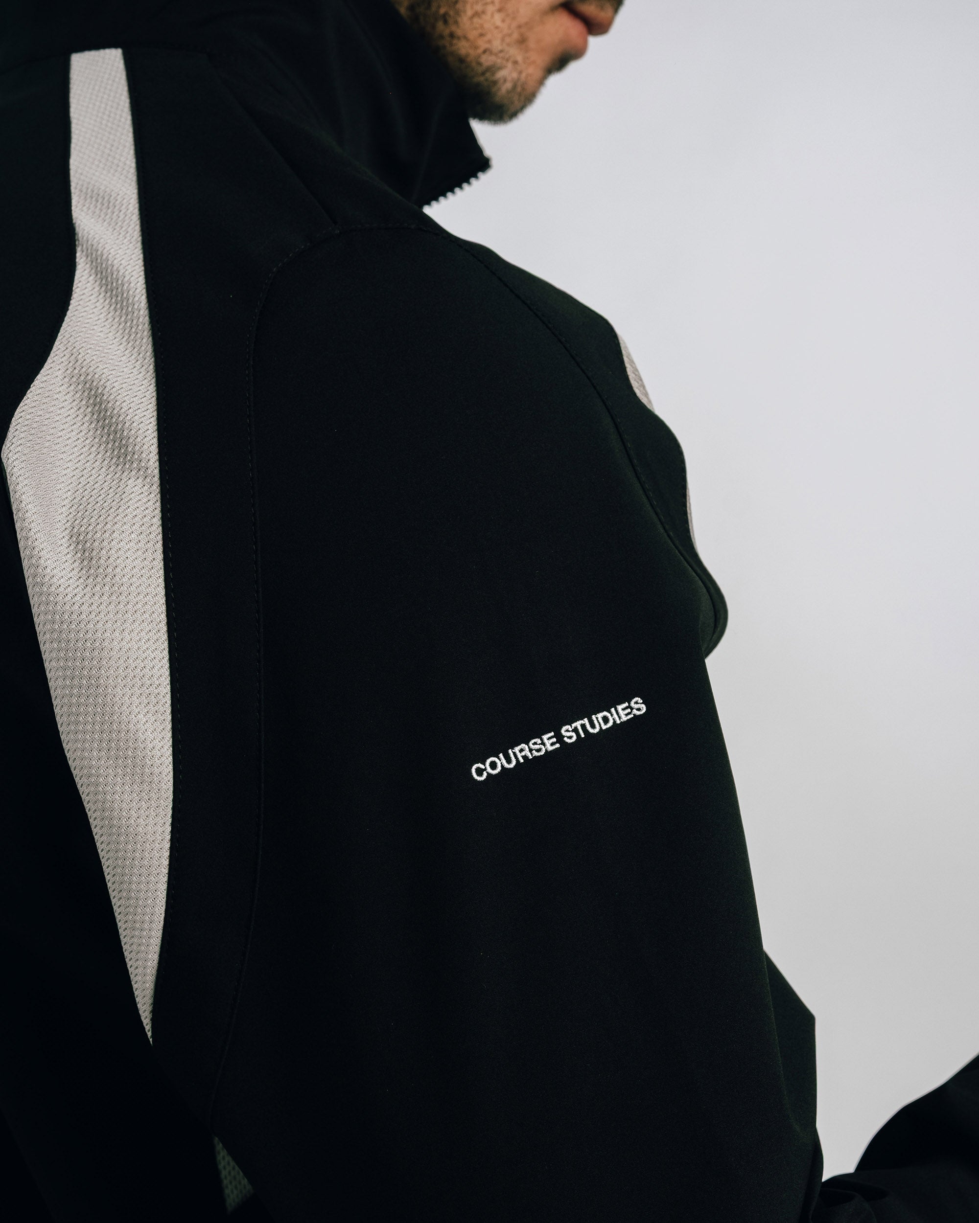 Person wearing a black jacket with 'Course Studies' branding on a light gray background