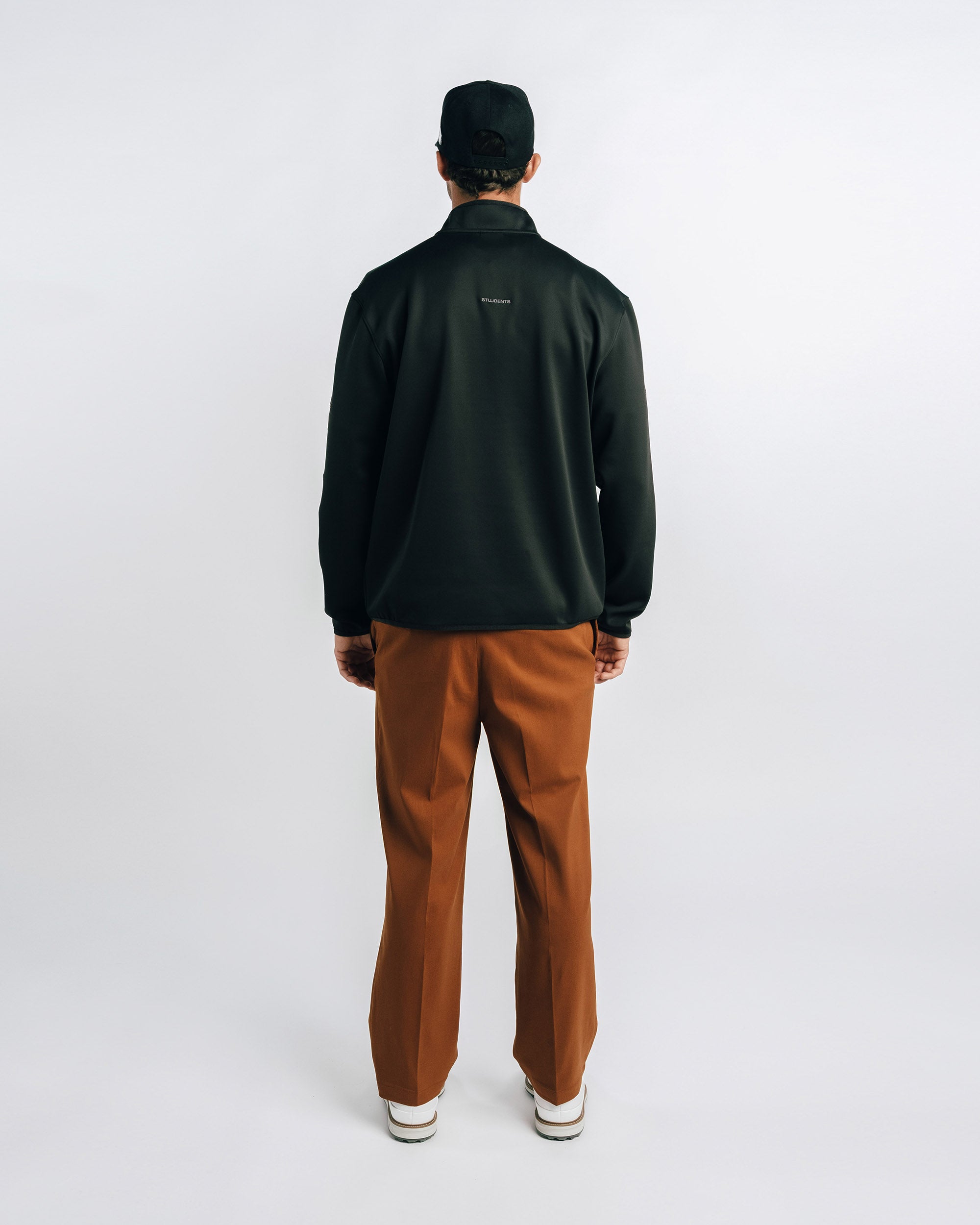 Person wearing a black jacket and brown pants on a white background