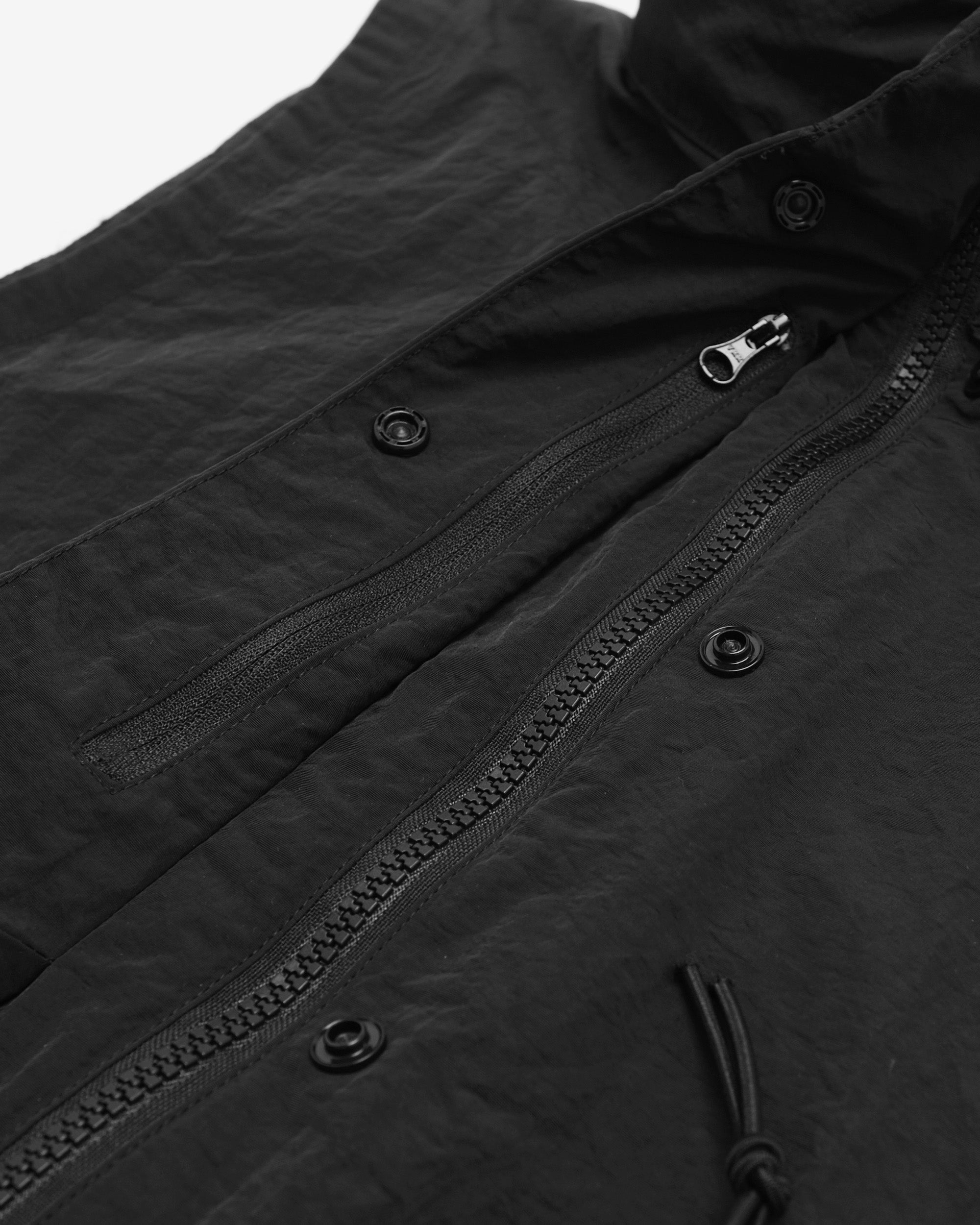 Close-up of a black jacket with zipper and button details on a white background
