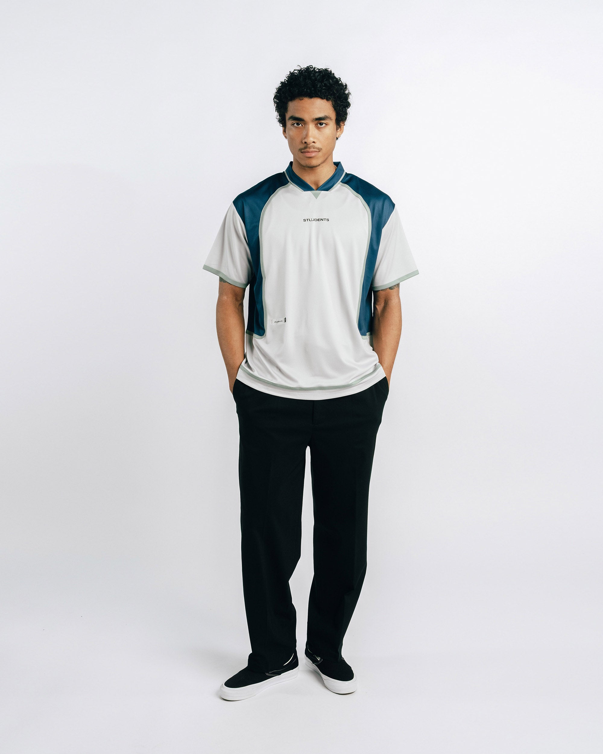 Person wearing a white and blue shirt with black pants on a white background