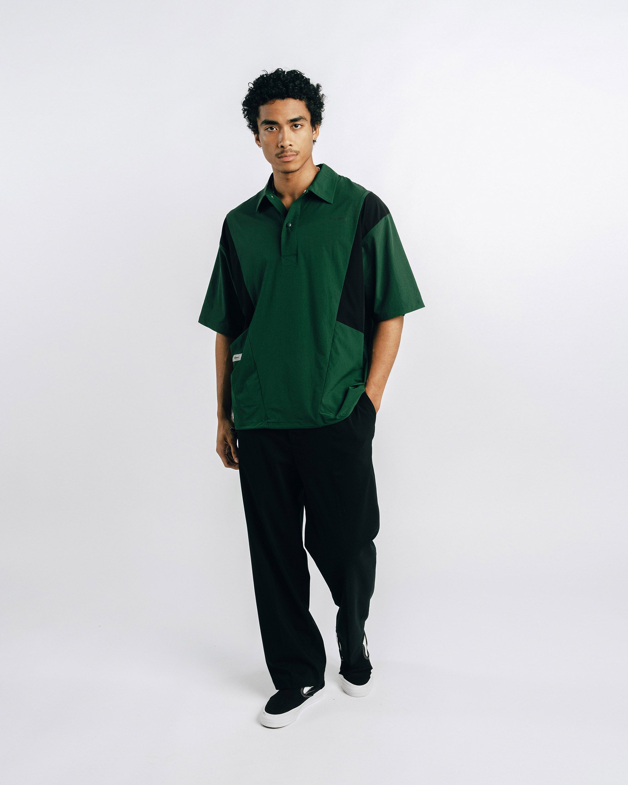 Person wearing green scrubs holding a black lanyard against a light gray background