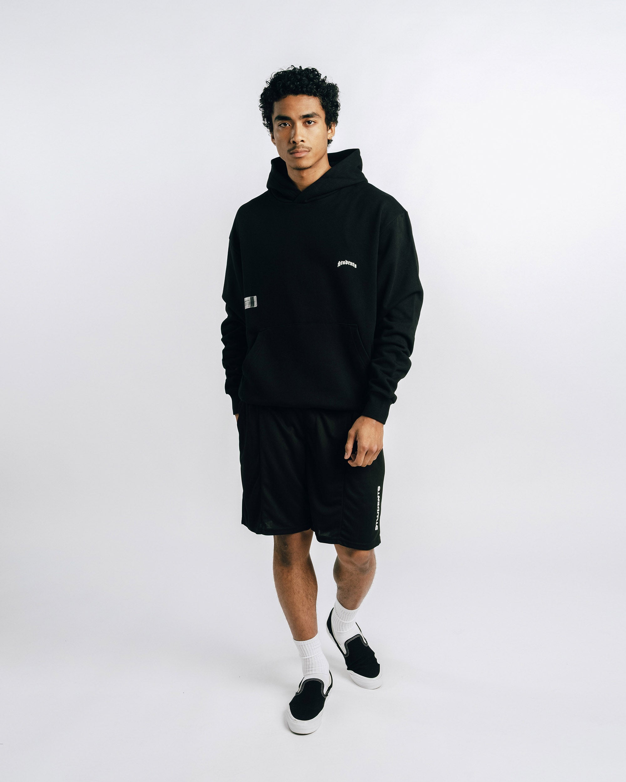 Person wearing a black hoodie and shorts set on a white background