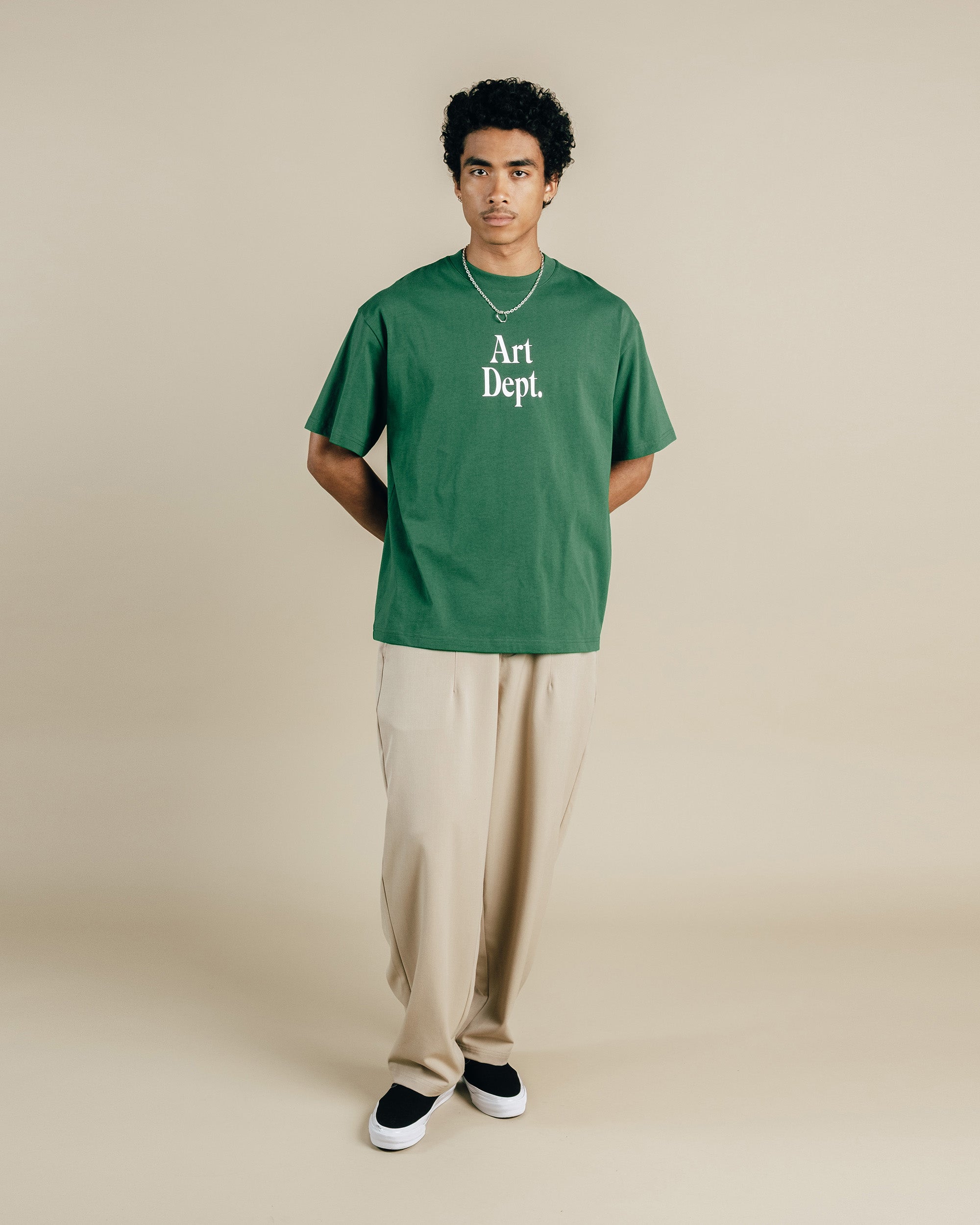Person wearing a green 'Art Dept.' t-shirt on a beige background