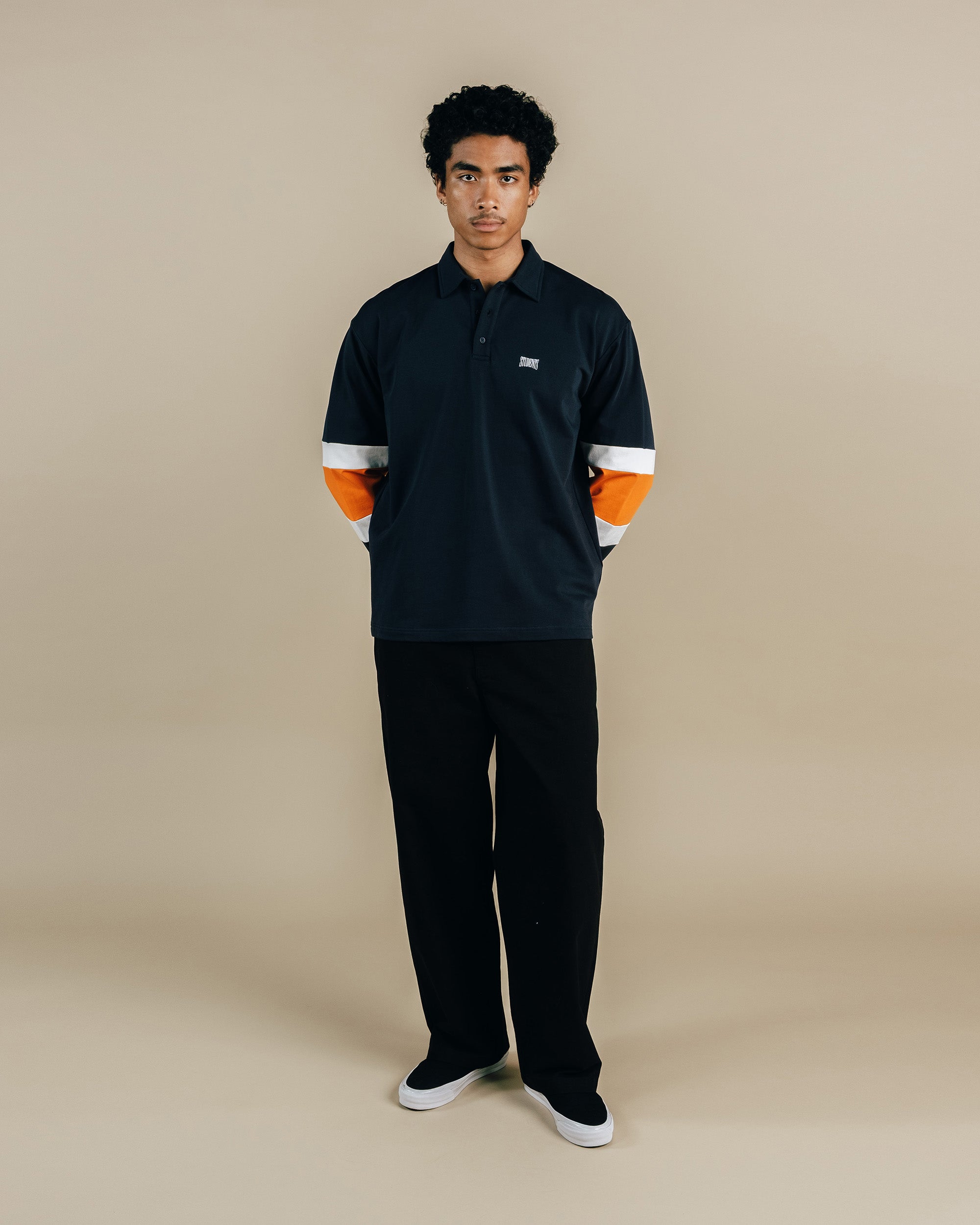 Person wearing a black and orange outfit on a beige background