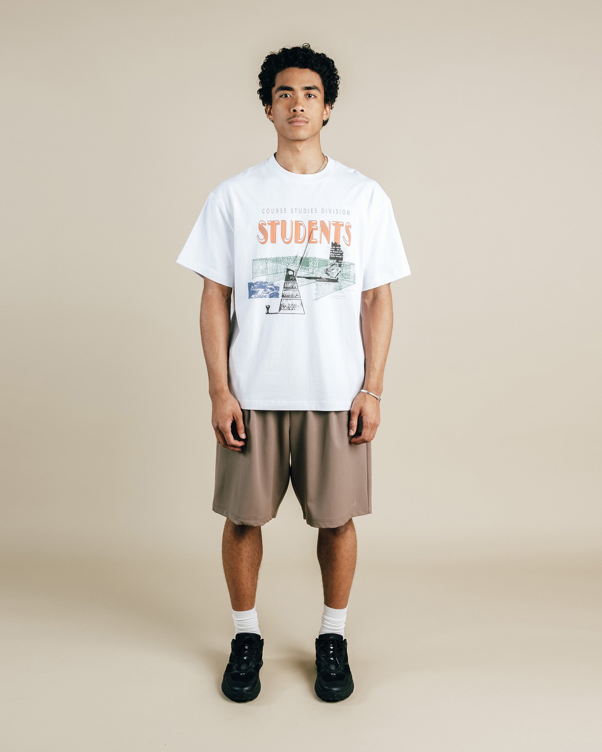 Person wearing a white t-shirt with graphics and text, standing against a beige background