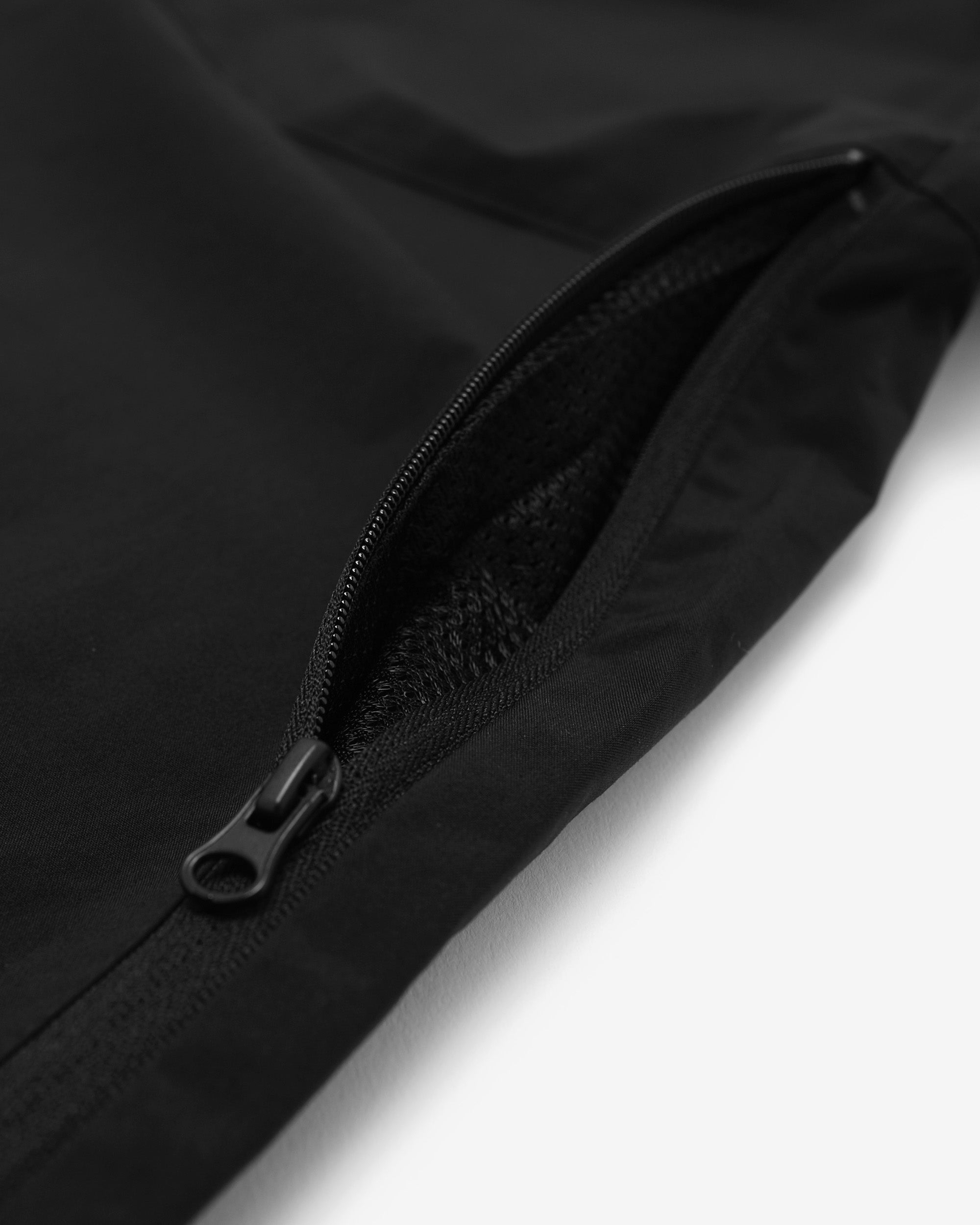 Close-up of a black zipper on a black jacket against a white background