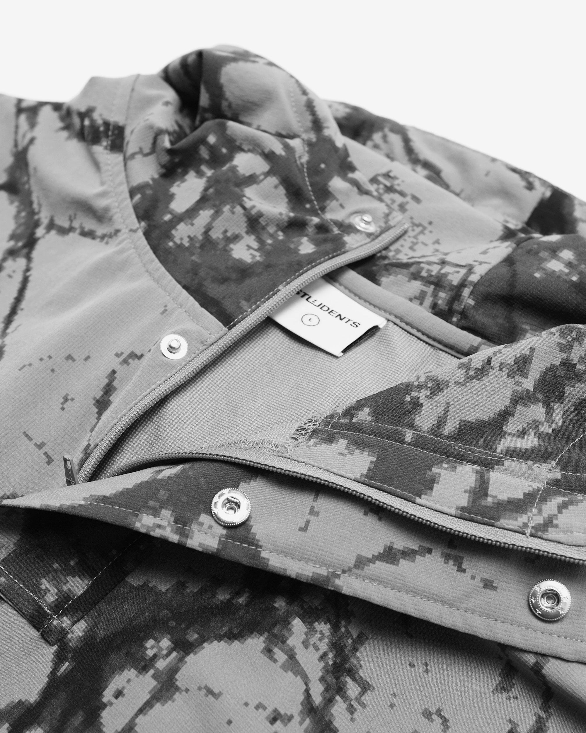 Close-up of a camouflage jacket with a brand label on a white background