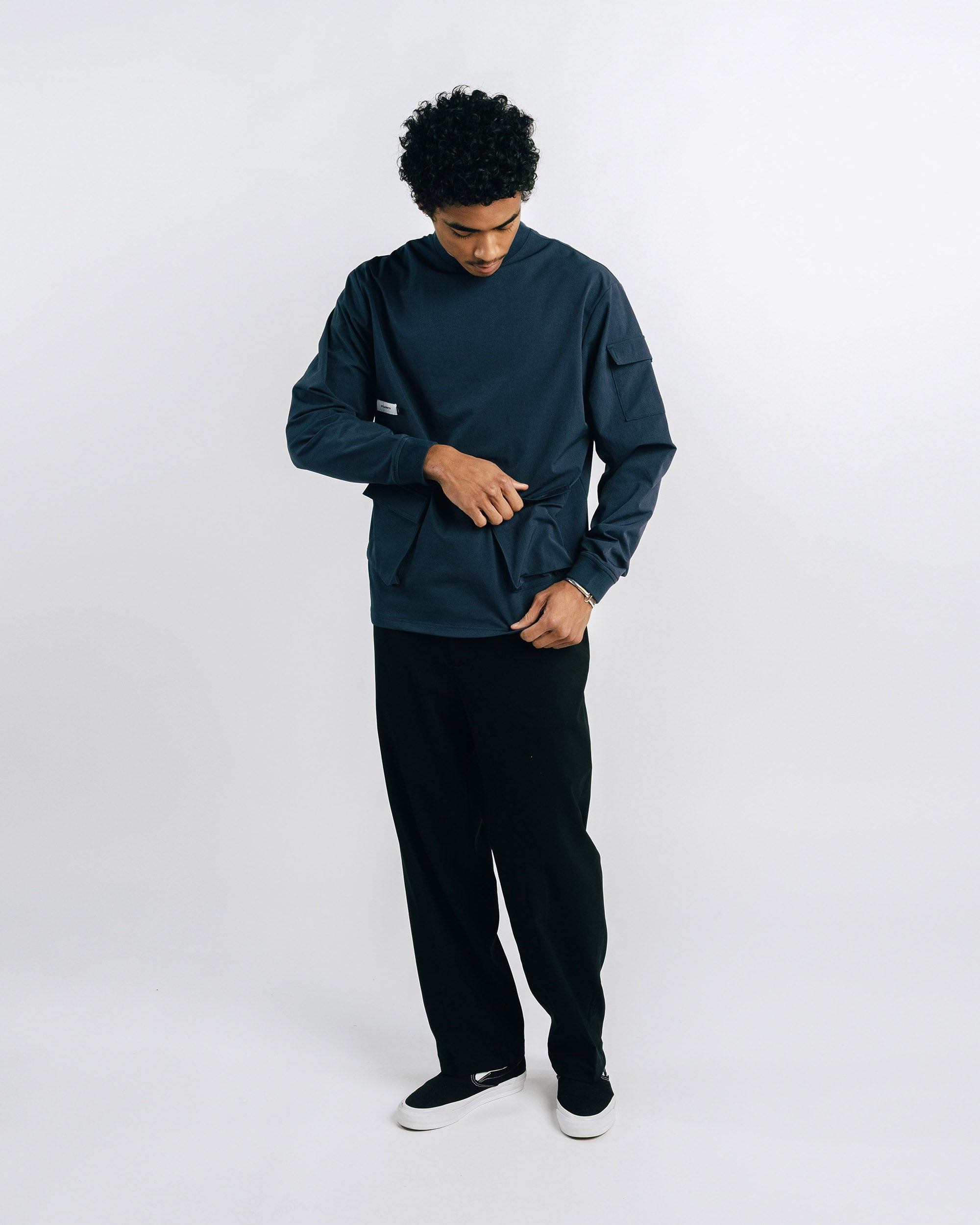 Person wearing a dark green jacket and black pants on a white background